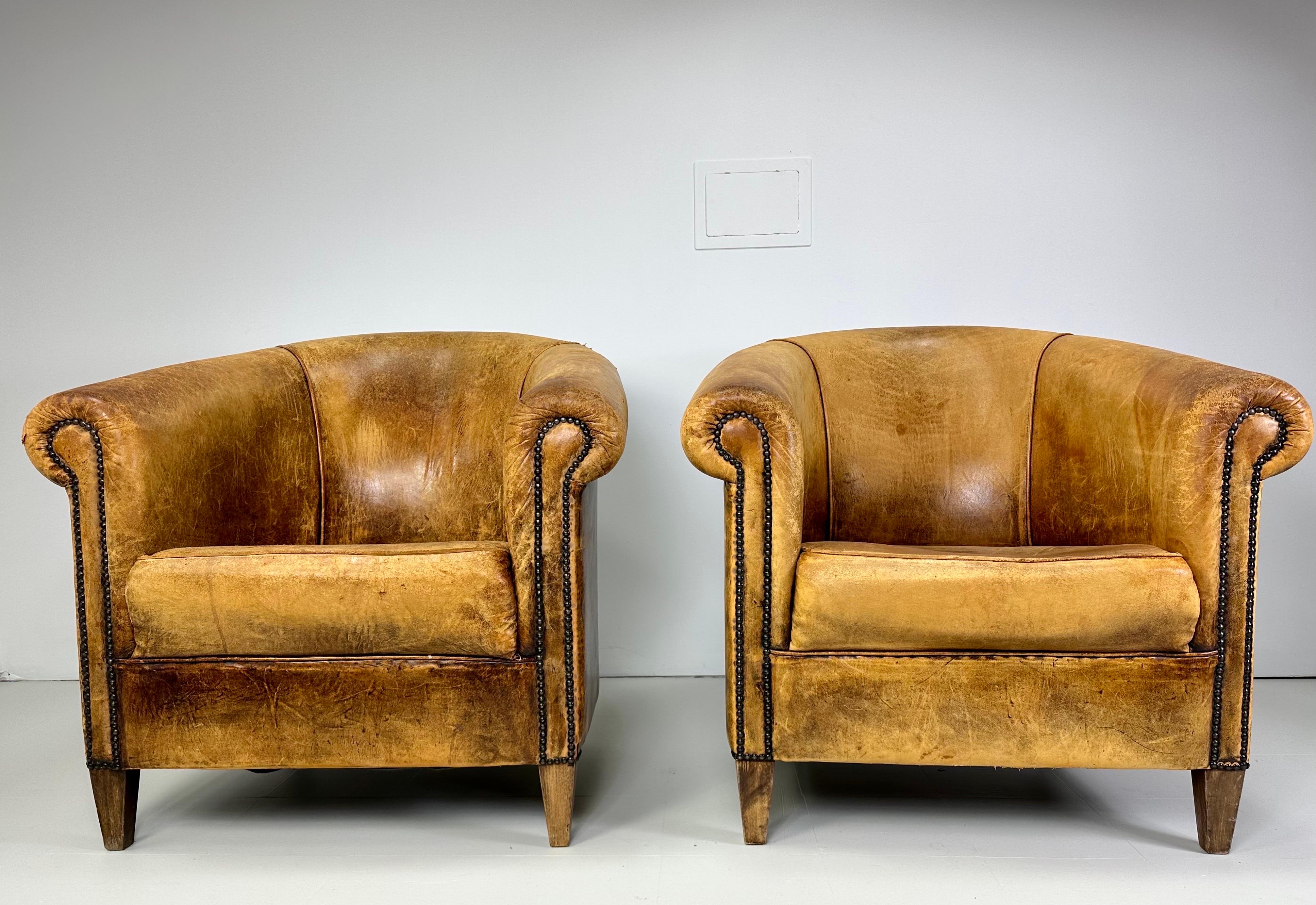 Early 20th Century Leather Club Chairs. Original cognac leather shows a well aged patina. Nail head details. Wood legs.

Delivery to NYC available for $425
