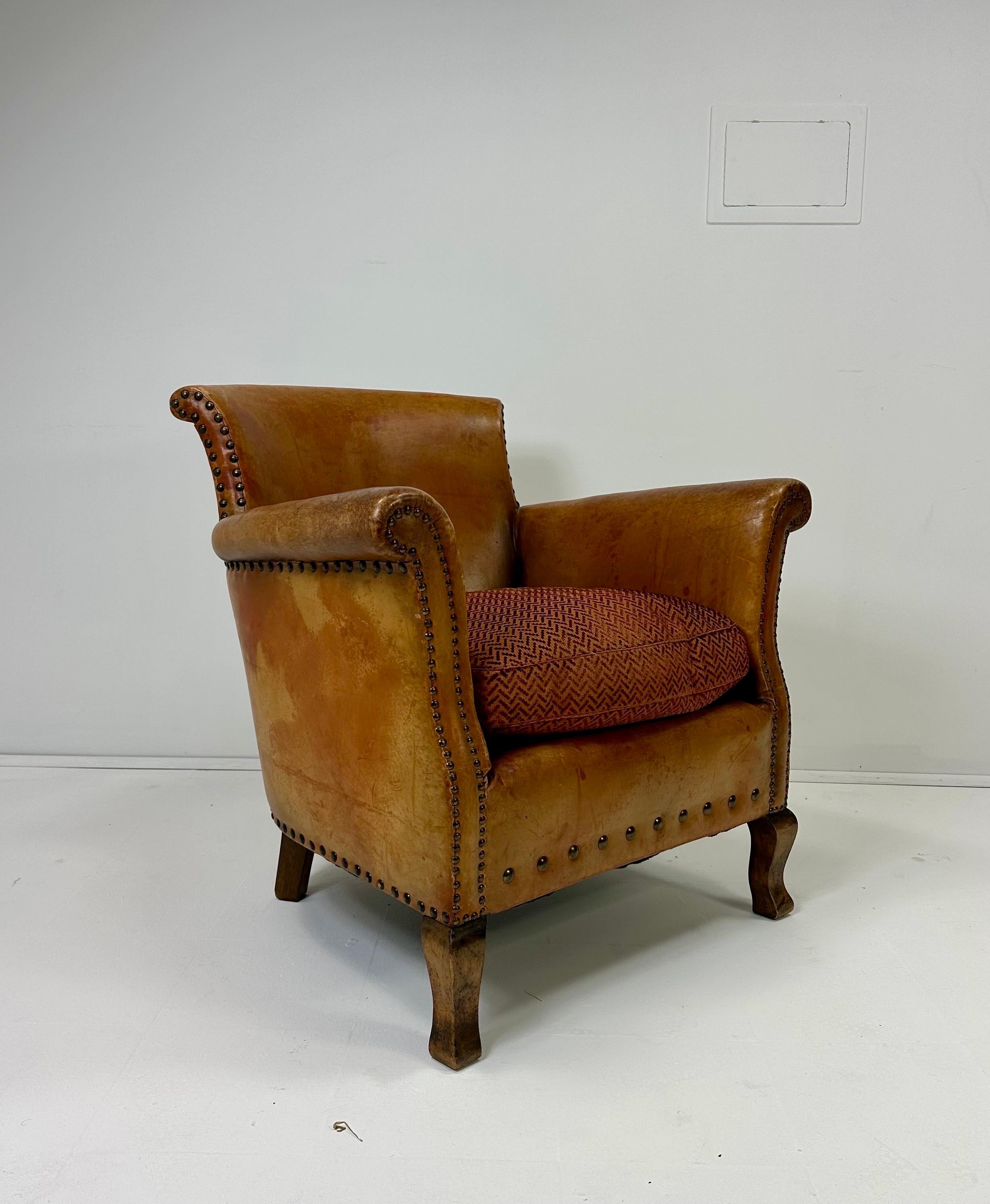 Sedia da salotto in pelle europea dei primi del Novecento.  Patina originale di pelle afflitta. Dettagli della testa di chiodo.  Gambe in Wood.  Sostituzione del cuscino del sedile.
Circa all'inizio del XX secolo.