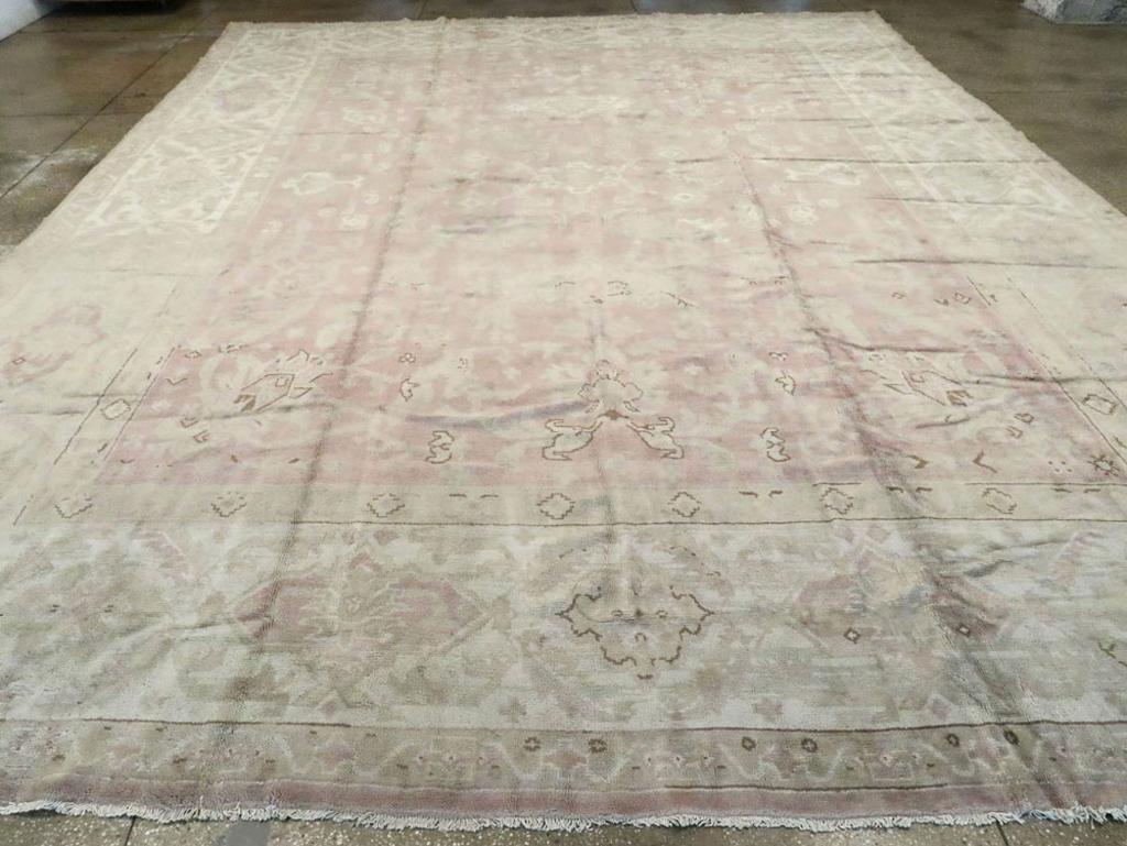 An antique European Oushak large carpet. This boldly drawn western Turkish workshop carpet has a field design including cartouches, aggressive corner palmettes and thick, truncated arabesques on the taupe ground. The beige main border features