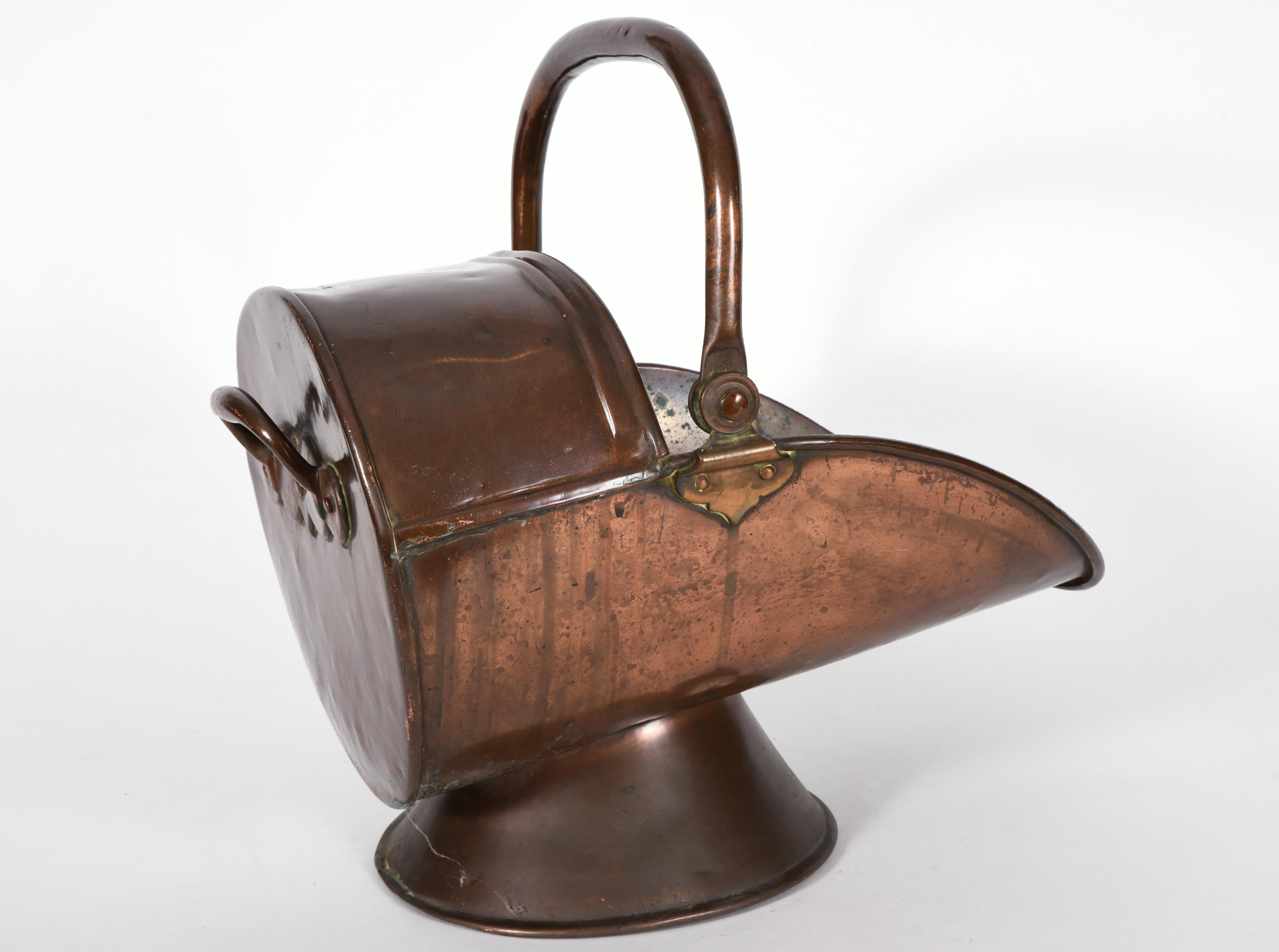 Early 20th century copper and brass coal or logs bucket with a heavy swing handle and stands off the floor on a slant. The coal or log bucket is in good used condition. The coal bucket measure about 11 inches high X 15 inches length X 8.5 base