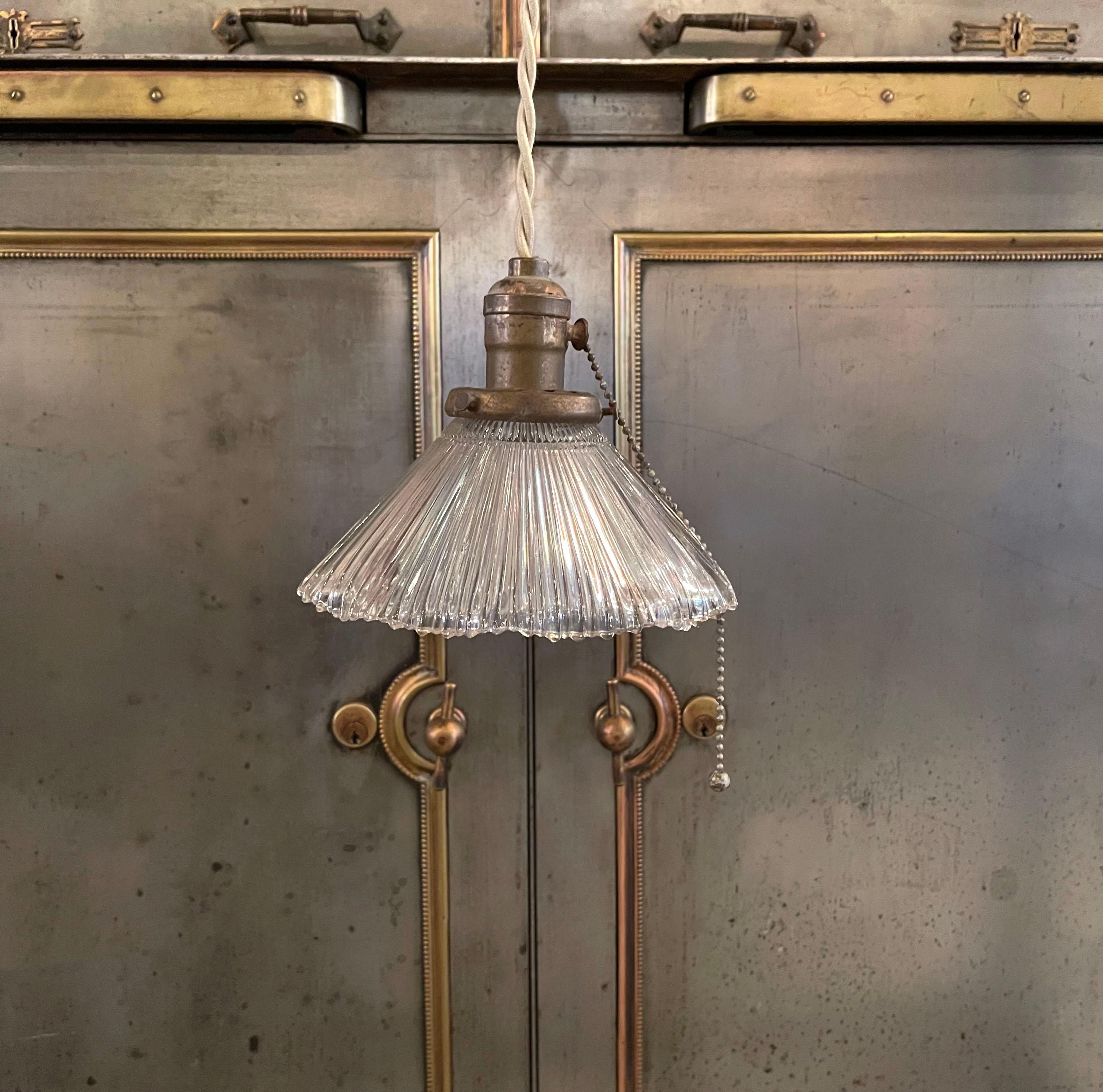 Petite, early 20th century pendant light with fluted glass shade with ruffled edge and brass pull chain hardware is newly wired with tan braided cloth cord to hang 77.25 inches overall.
