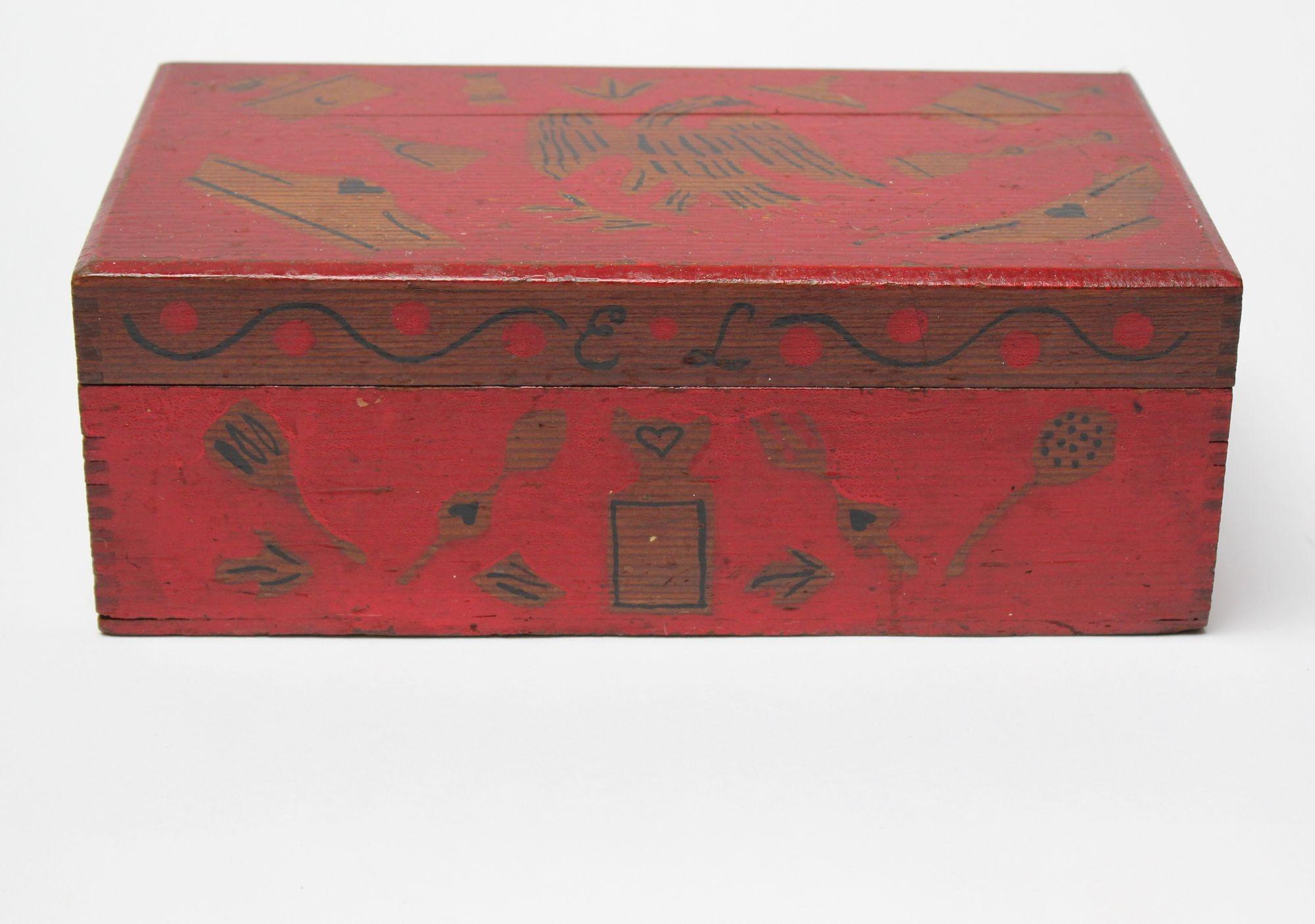 Folk art decorative box with eagle motif in attractive red paint (ca. 1910-1920, USA). The hinged top opens to reveal a divided storage compartment, perfect for housing small accessories (jewelry, cufflinks, etc.). 
Imagery is created in a