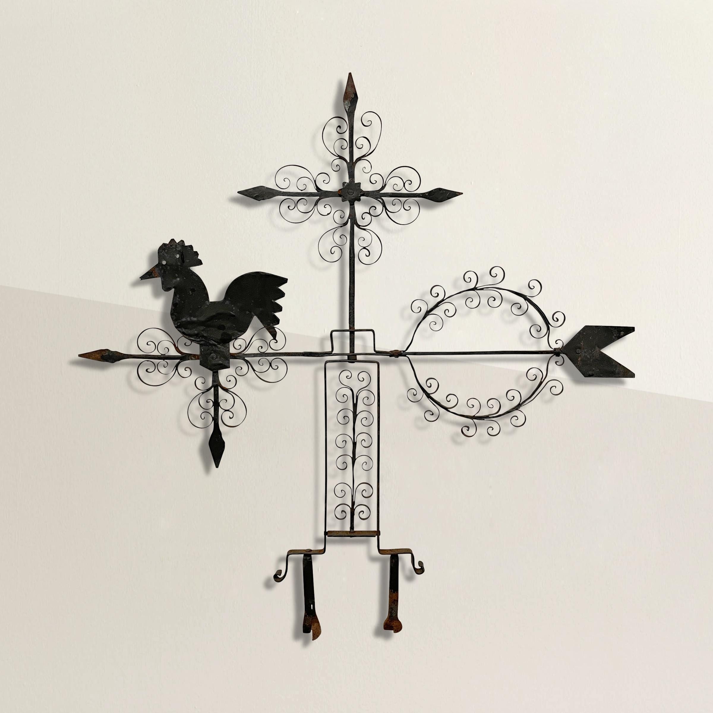 A wonderfully whimsical early 20th century Folk Art hand-wrought iron weathervane with a rooster standing on the tip of the arrow, a greek cross at top, and a wreath at the back of the arrow, and all decorated with hand-wrought curly floral