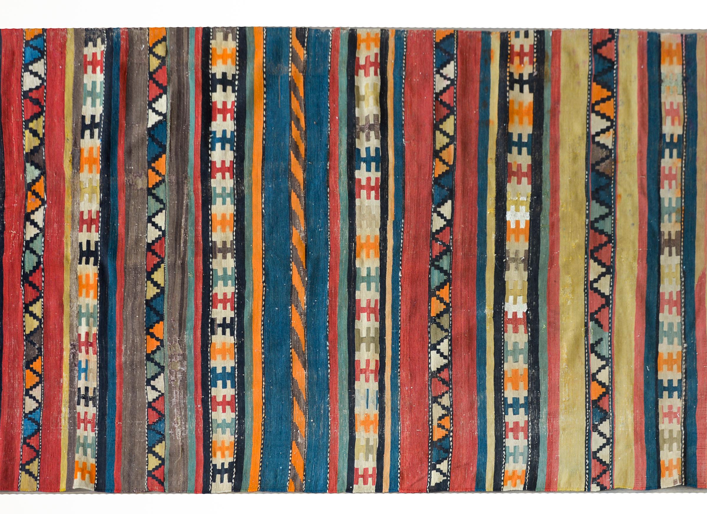 A wonderful early 20th century Persian Shahsevan kilim runner with myriad multi-colored stripes, some solid, and some with geometric patterns, and all woven in brilliant bold colors.