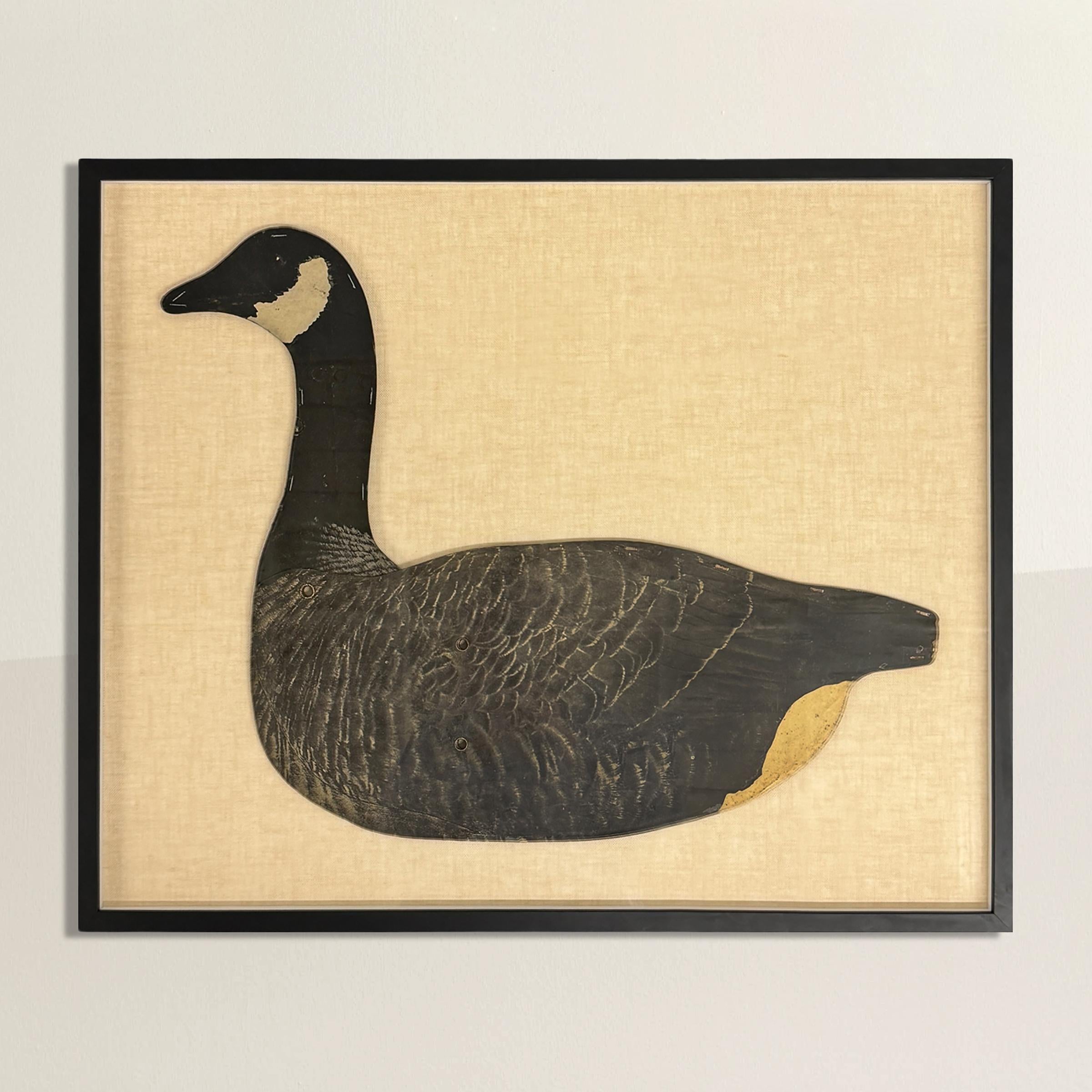 This framed American 1940s Canada Goose decoy is a striking piece of functional folk art, beautifully preserved and presented. Originally crafted from waxed cardboard, the decoy was designed to be lightweight and portable, with a metal bar inserted