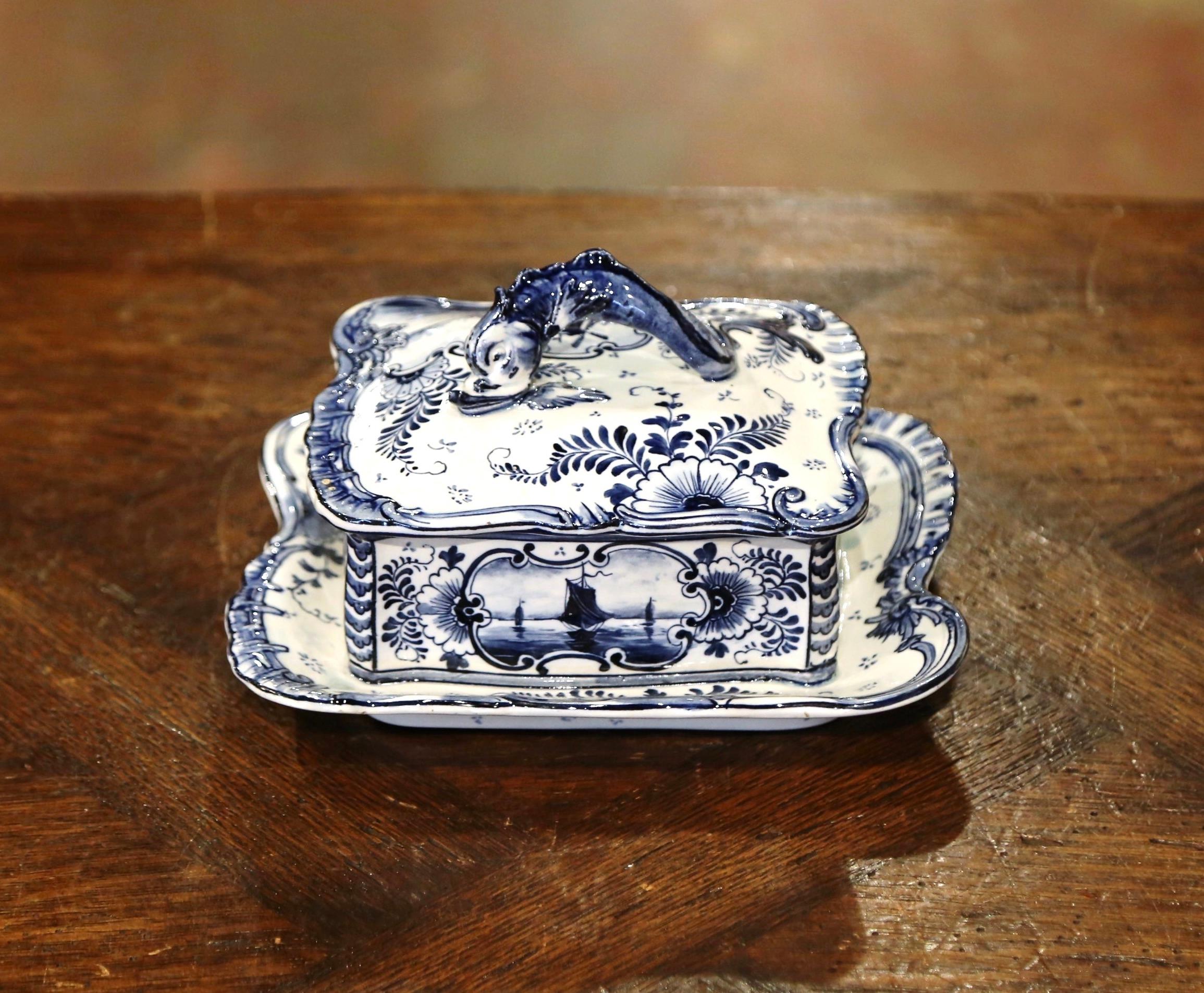 This faience decorative box was crafted in Germany, circa 1900; attributed to Royal Bonn (trade name for Franz Anton Mehlem), the dish is rectangular in shape and sits on an attached platter base. It features a figural dolphin in high relief as the
