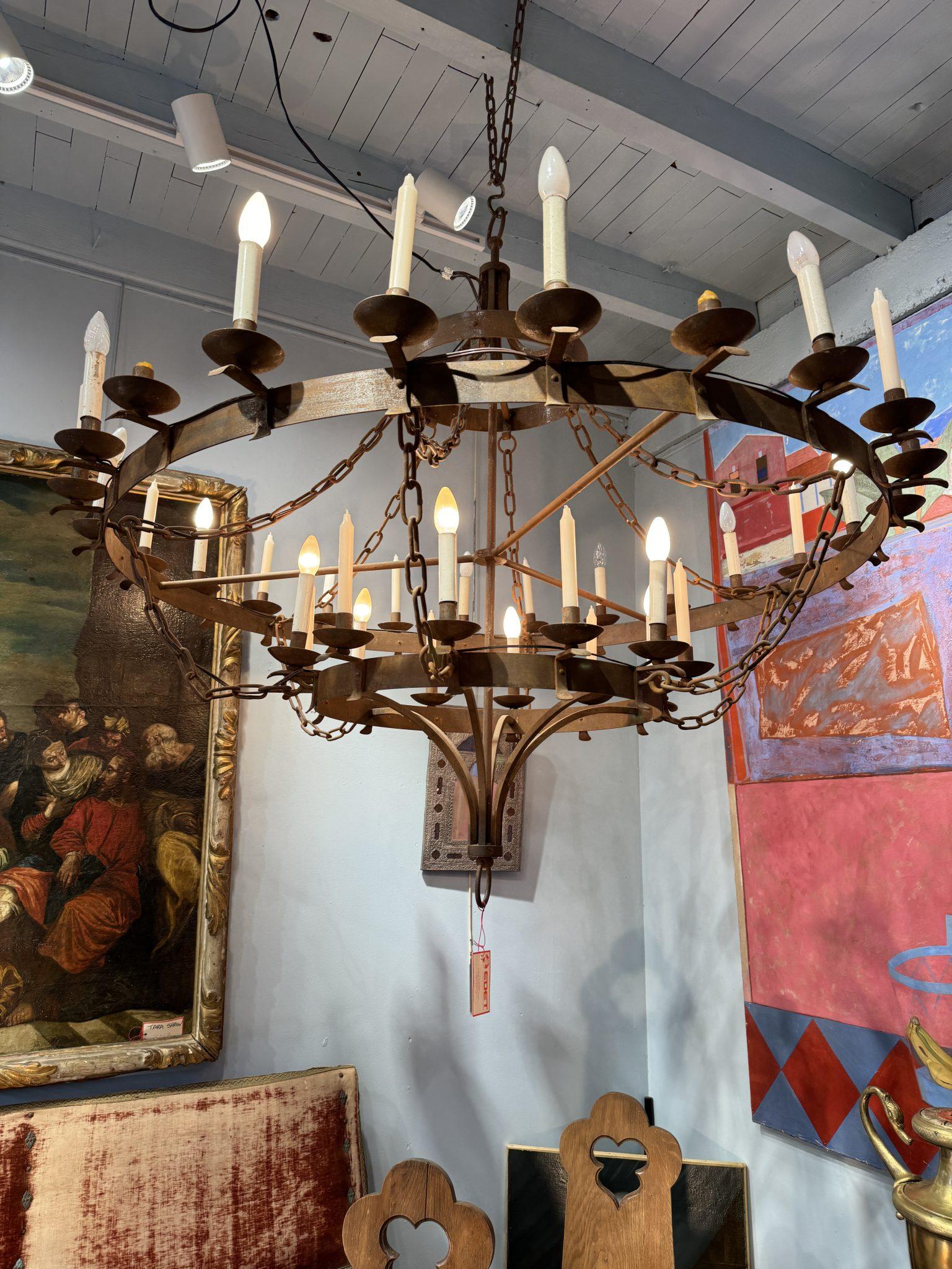 Il s'agit d'un lustre français du début du 20e siècle comprenant 36 lumières, provenant d'un château près de Paris. Son design circulaire grandiose est réalisé en fer forgé, créant une esthétique à la fois rustique et élégante. Le lustre est orné de
