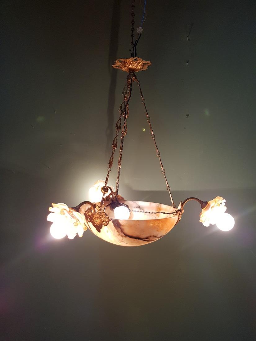 Antique French rose-colored alabaster chandelier with 3 arms with rose-colored glass caps and gold-colored bronze frame (original bayonet fitting and electrically refurbished), first quarter of the 20th century. 

The measurements are:
Depth 60