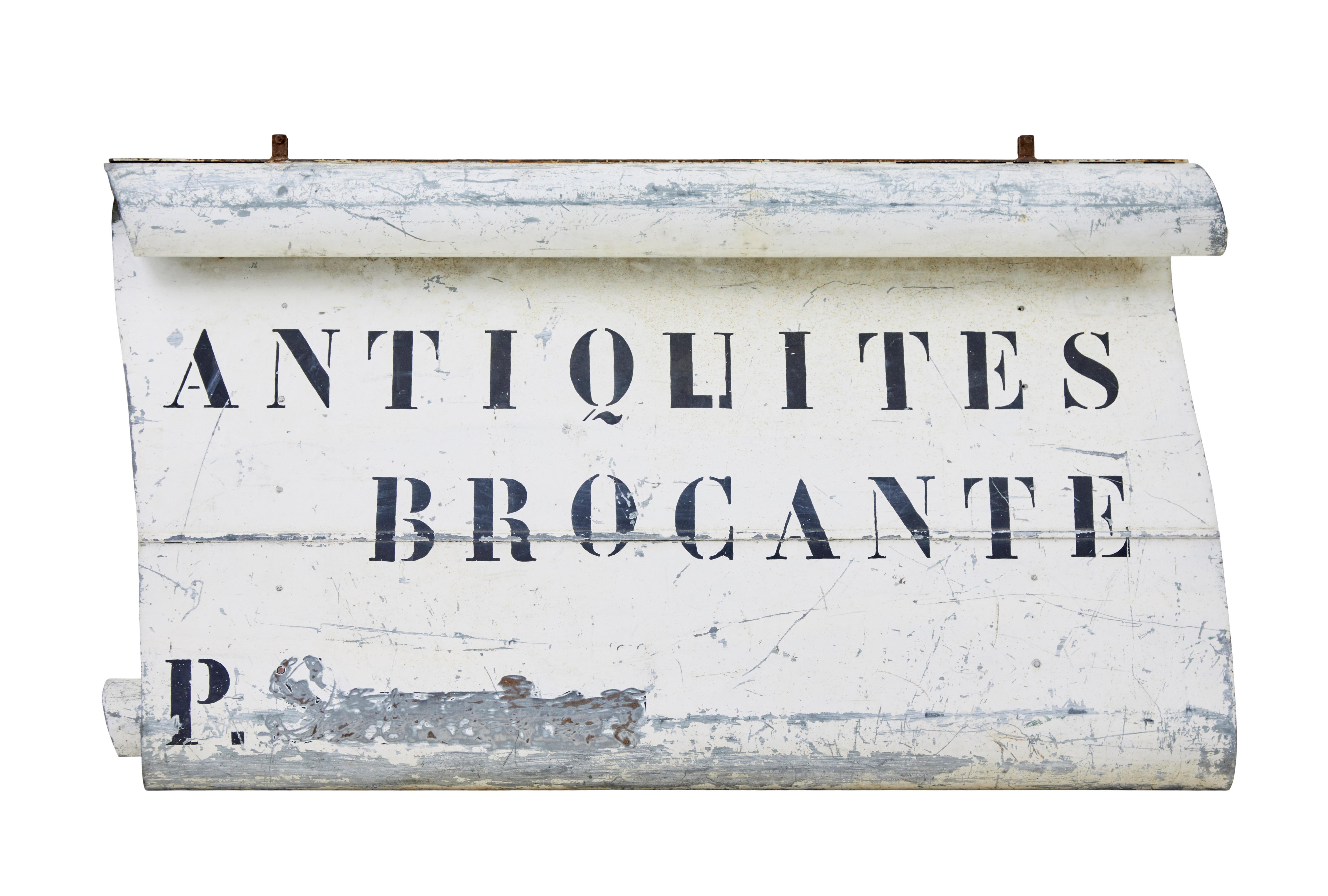 Here we present an unusual find of a french antique shop sign, circa 1920.

Shaped steel, painted with applied lettering in french which reads 'antiques and secondhand goods'.  The dealers name has been crudly scratched out.

Brackets remain to the