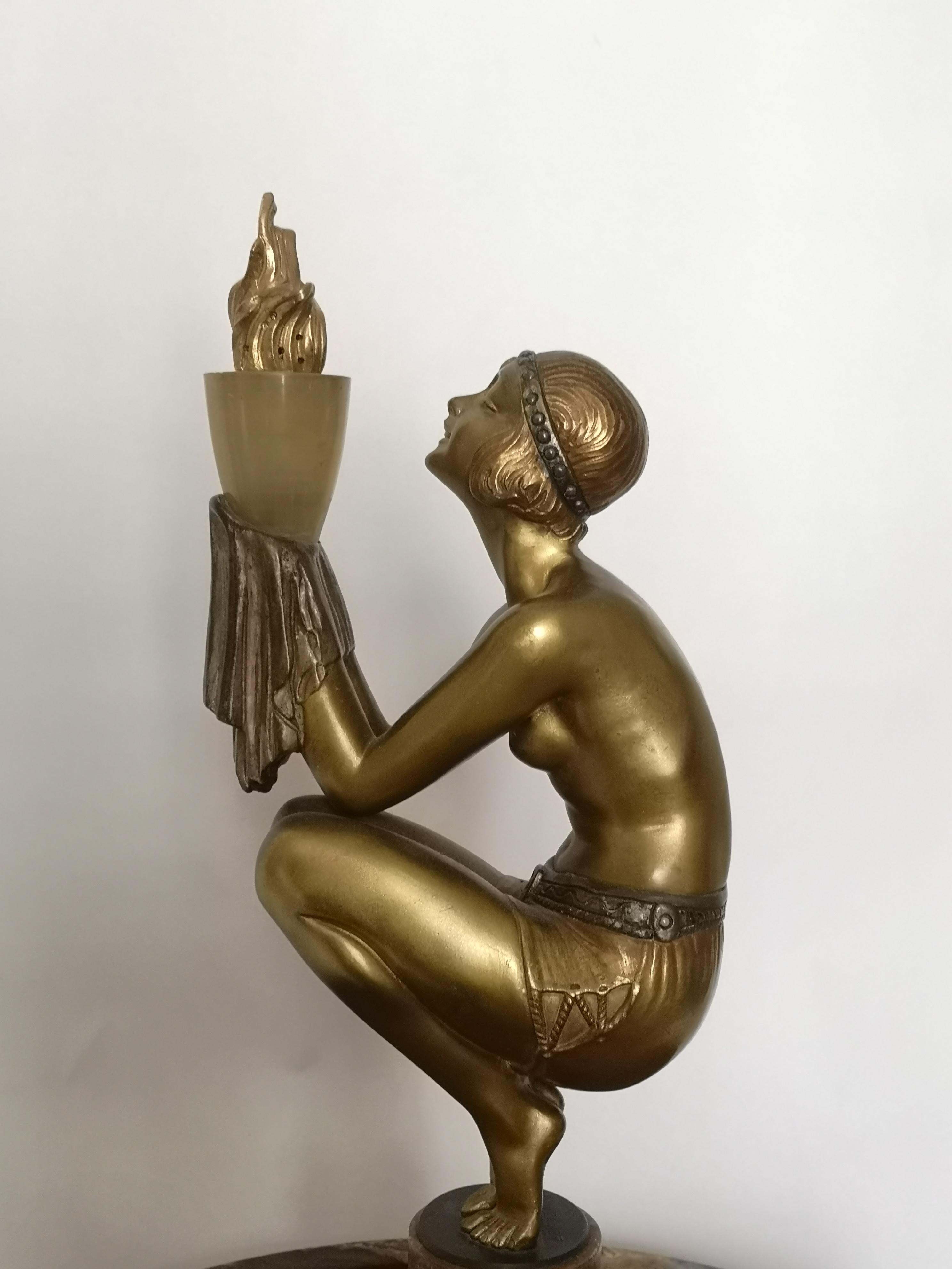 This Art Deco sculpture, designed as a cold painted gilt bronze crouching 1920s dancer holding a light with an ormolu flame in her hands, raised in the centre of a circular onyx base. Signed at the base of the bronze.
Duvernet is well known for his