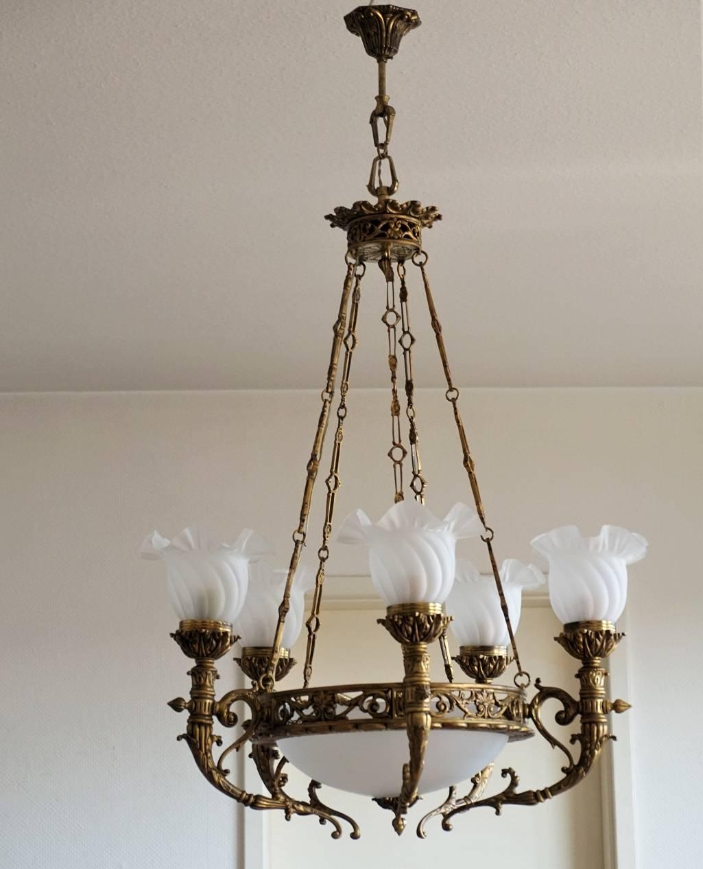 A large Art Deco gilt bronze seven-light chandelier, France circa 1920, crown-shaped with frosted glass bowl surrounded by five lamp arms with frosted glass shades. Five hanging chains connected to a decorative canopy. 

Measures:
Height 45.50 in