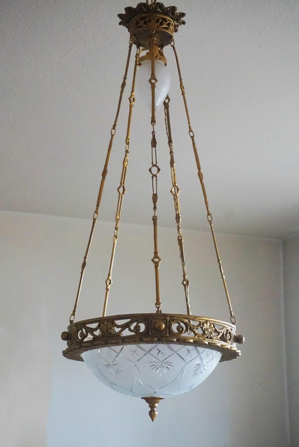 Magnifique lustre Art déco au design très élégant, en forme de couronne en bronze doré, avec un abat-jour en verre satiné taillé à la main et un petit abat-jour suspendu au sommet, le tout soutenu par cinq chaînes en bronze reliées à un baldaquin