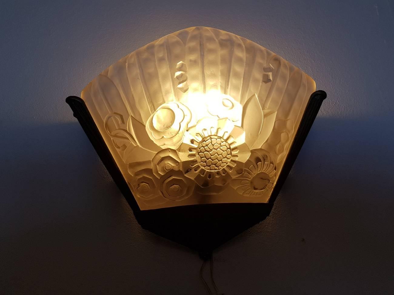 French Art Deco bronze wall sconce circa 1930 with pressed glass shade decorated with flowers in relief (the glass has some chips around the edge but not visible from outside).

The measurements are:
Depth 13.5 cm/ 5.3 inch.
Width 33 cm/ 12.9