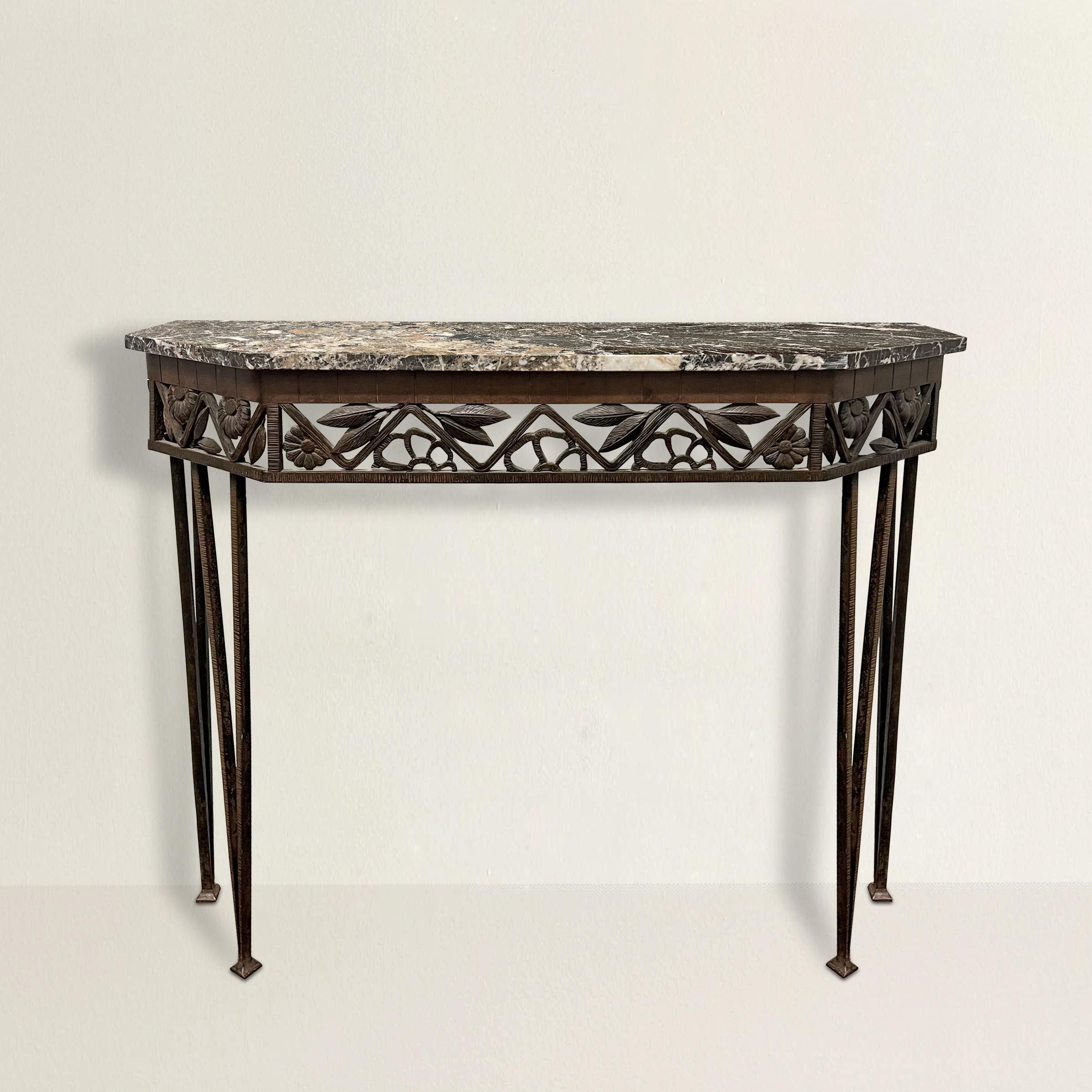 A stunning early 20th century French Art Deco Fer Forgé console table with a hand-wrought iron base with flowers and leaves, some in relief and some in profile, tapered legs, and a polished marble top.  The perfect table for your foyer, or hallway. 