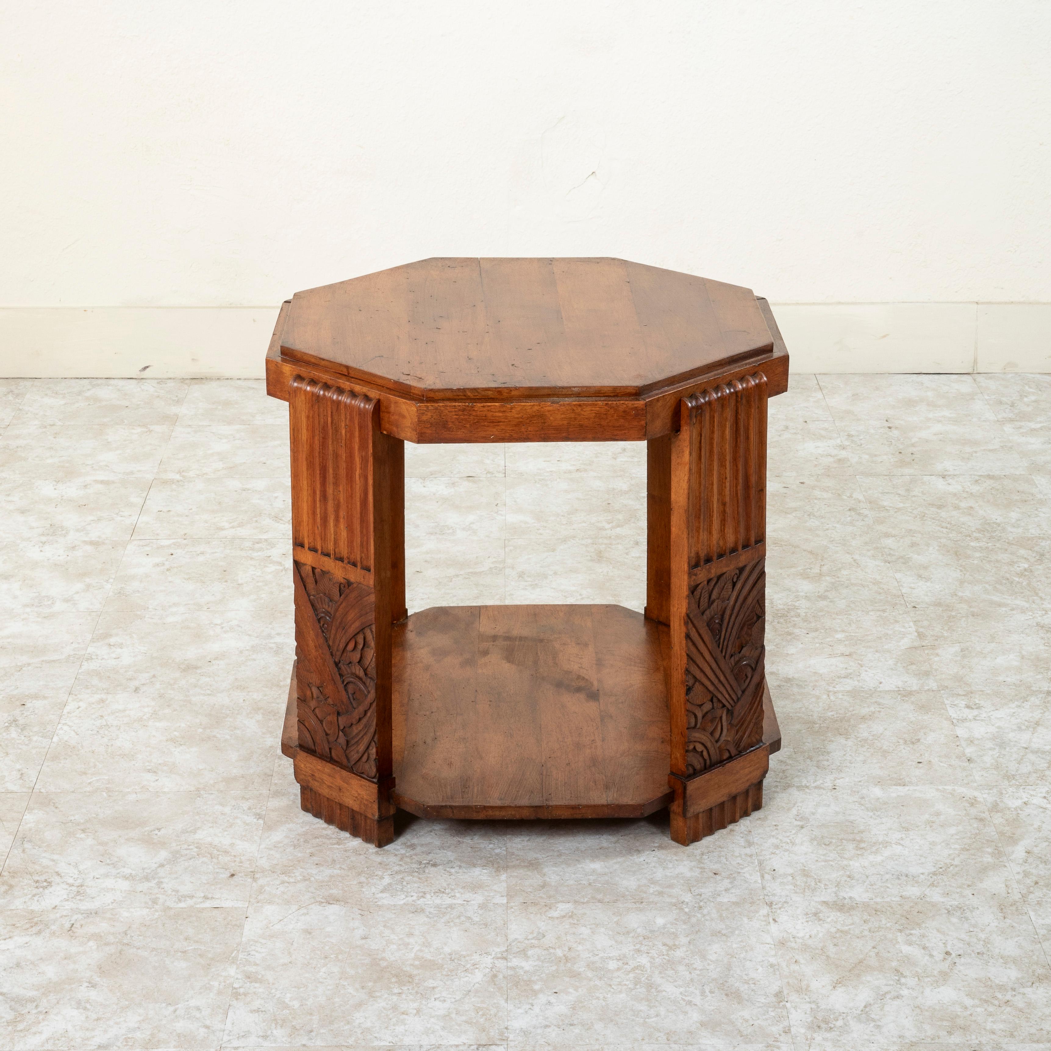 This early twentieth Century French Art Deco period walnut cocktail table or side table features an octagonal top. The top rests on four legs detailed with fluting on the upper half and carved stylized flowers and leaves on the lower half. A lower