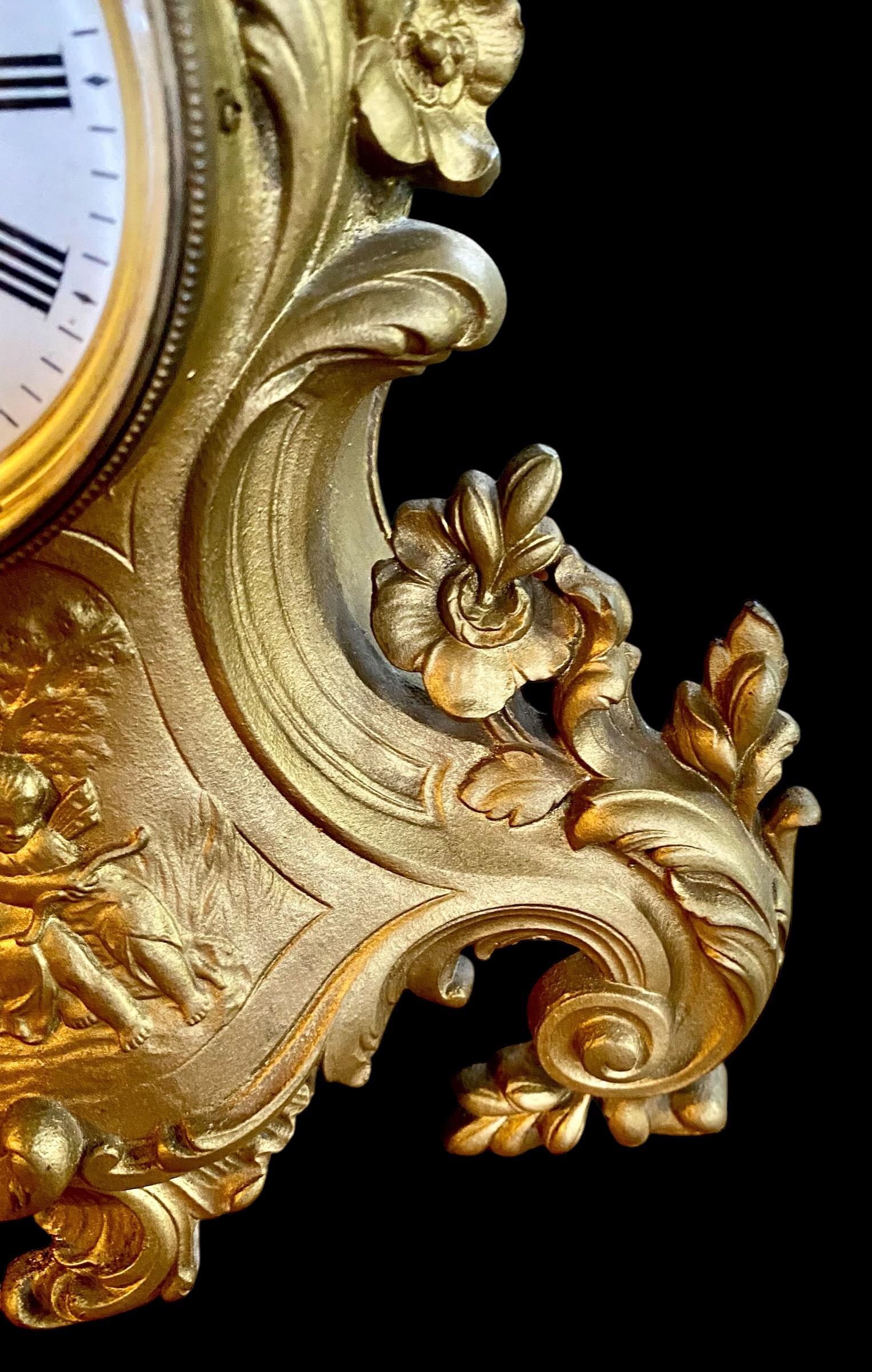 An antique early 20th century French Art Nouveau mantle clock with Roman numeral chapter ring and crystal bezel. The case with foliage and floral decoration, the center with a scene of cherubs frolicking in a garden. 
Key included.