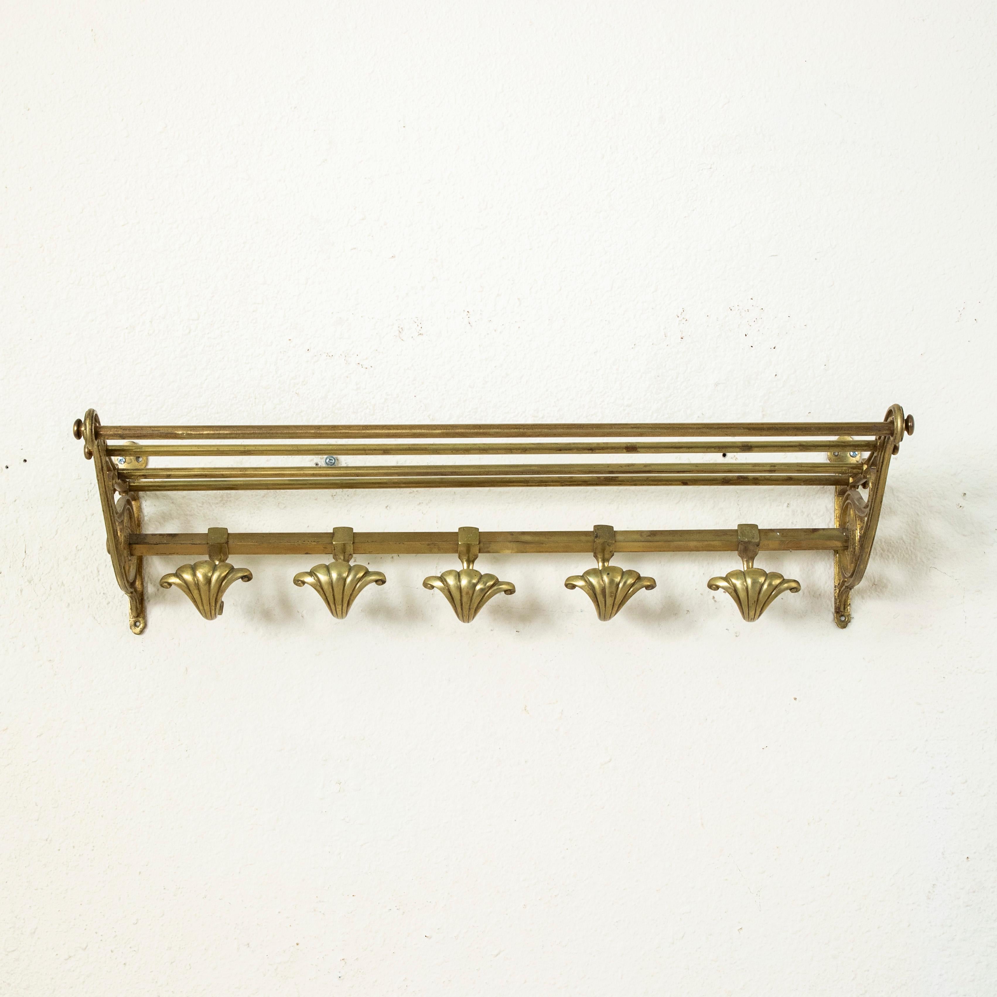 Originally from the cabin of a train, this French bronze hat and coat rack from the turn of the twentieth century features an upper shelf and five sliding hooks in the shape of shells. The brackets at the ends are detailed with scrolling and