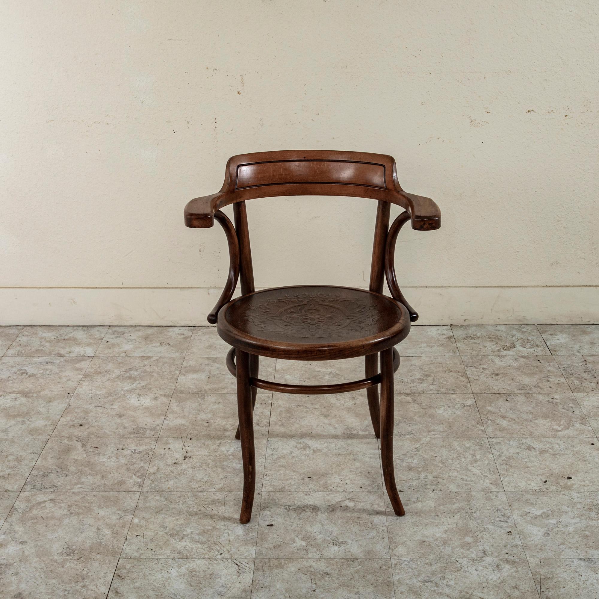 Attributed to Thonet, this French Art Nouveau period bentwood armchair features a pressed wood seat detailed with a classic central rosette and scrolling leaves. The curved seat back and armrests are supported by curved braces and the seat rests on