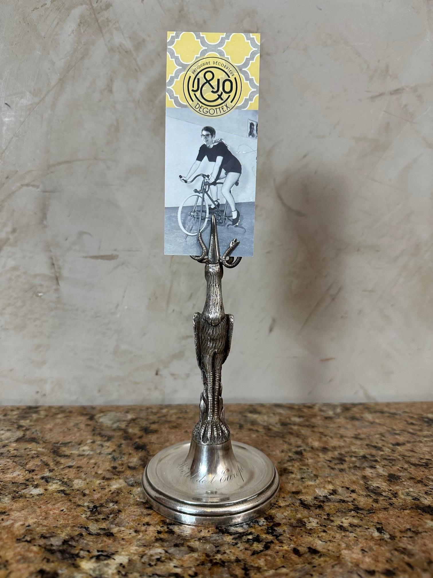 Superb silver-plated menu holder dating from the early 20th century, made especially for the Hôtel de l’Europe.

The stand is finely crafted in the shape of a standing bird, elegantly sculpted, resting on a circular base engraved with the name of