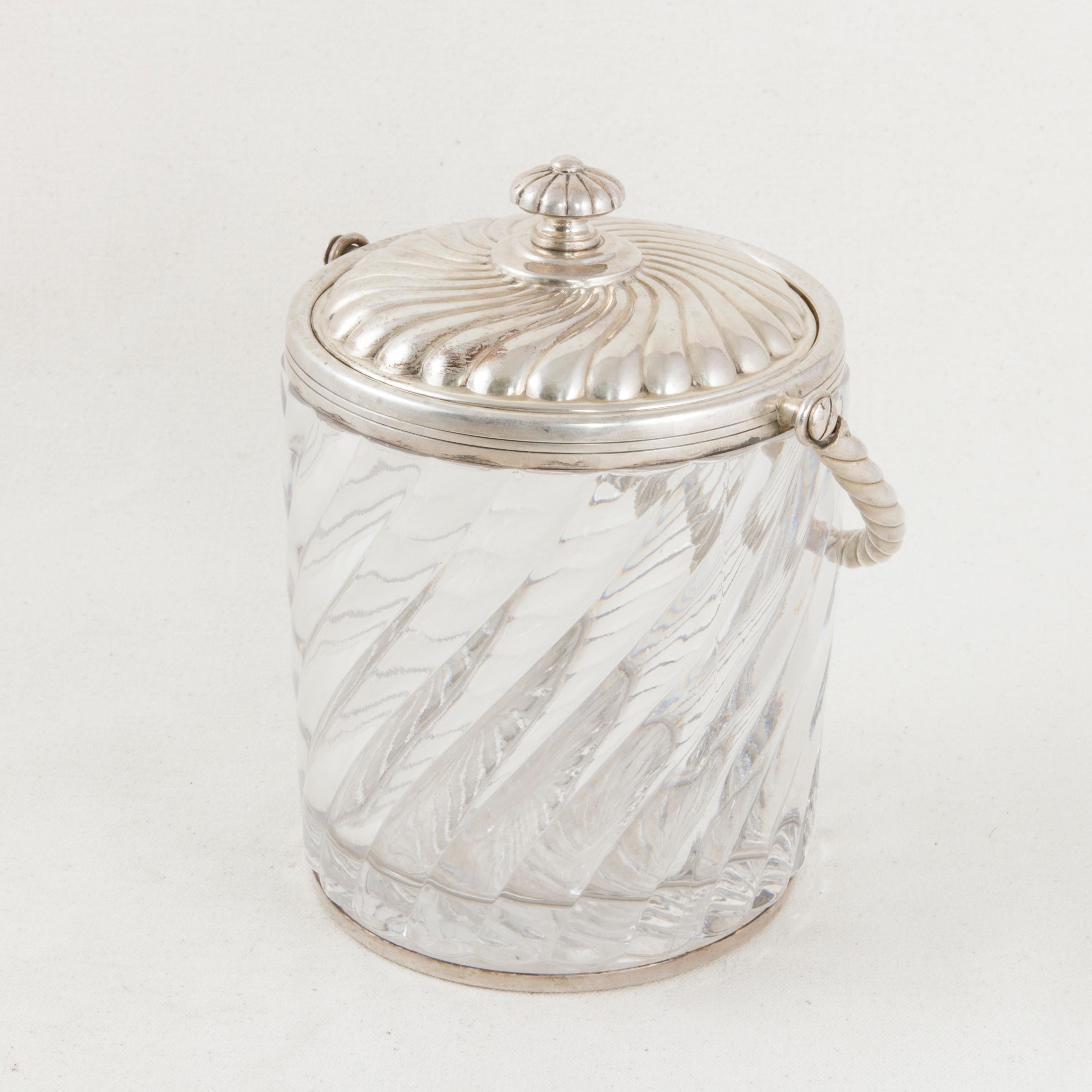 This early 20th century French ice bucket features a crystal bowl marked Baccarat Depose or Trademarked Baccarat on the bottom of the interior. A sterling silver band around the top holds a handle in place and is stamped with silver hallmarks. A