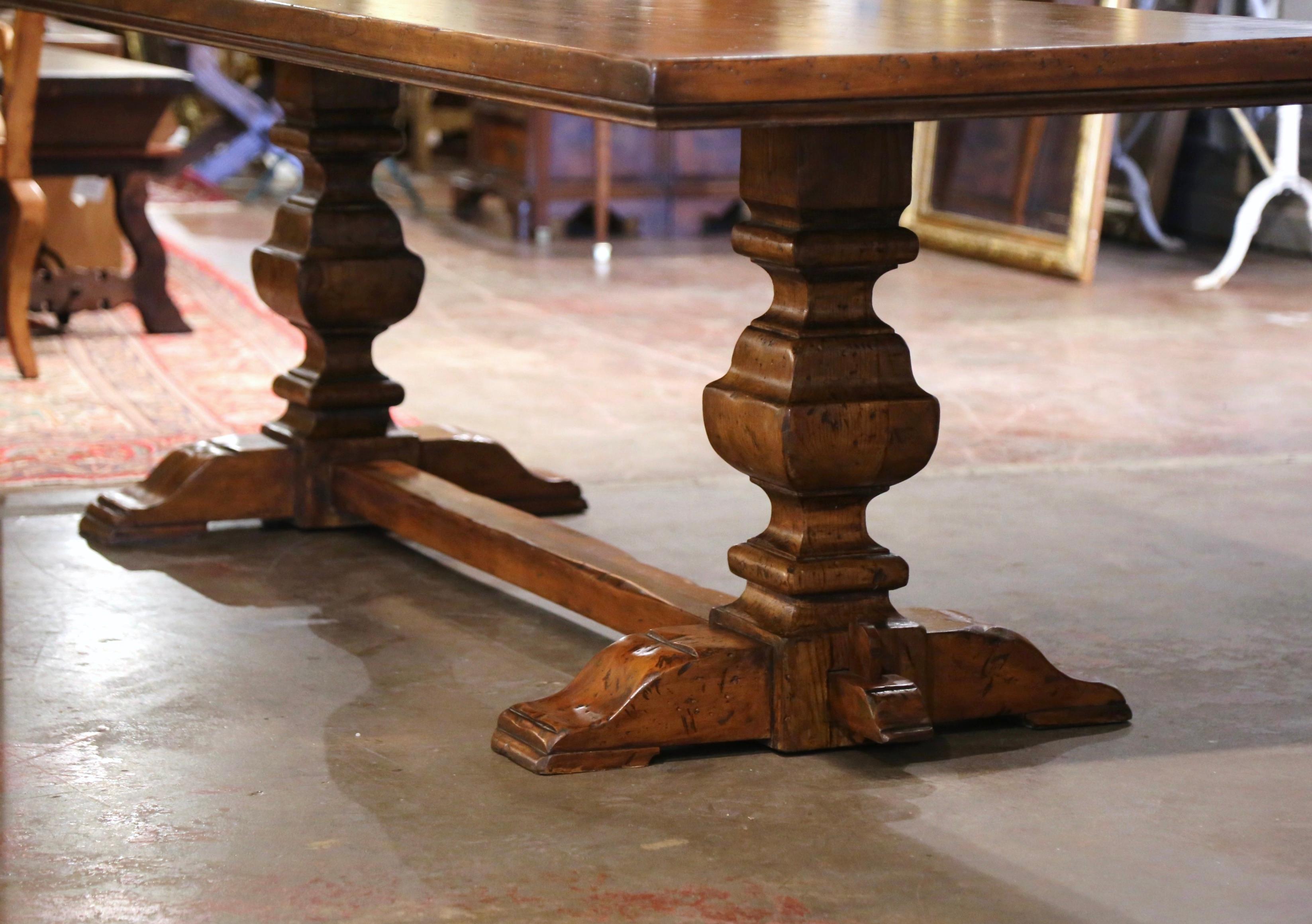 This elegant antique dining table was crafted in France, circa 1920. Standing on two carved baluster support legs ending with molded shoe feet and joined with a bottom stretcher with wedged mortise and tenon joinery, the Baroque monastery table is