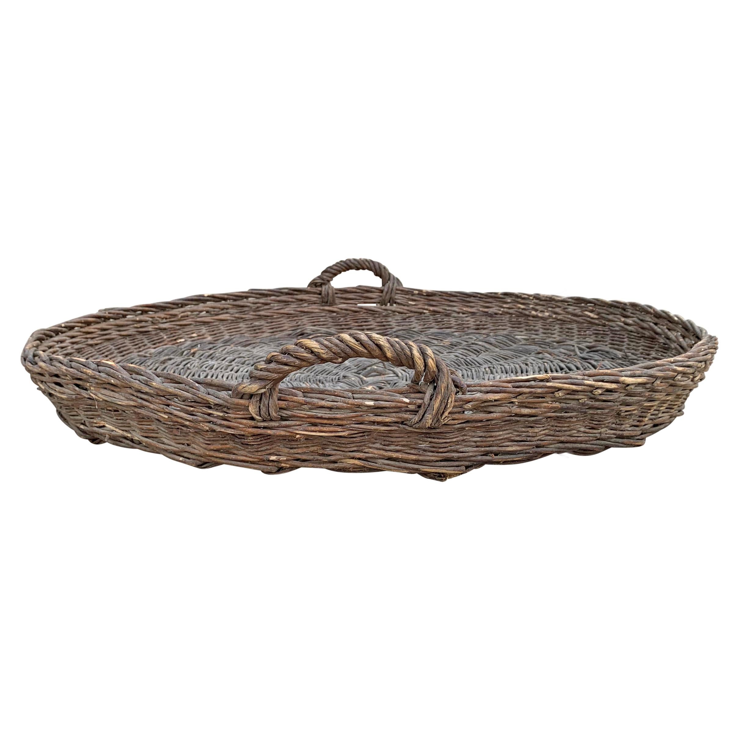 An early 20th century French handwoven willow winnowing basket with two twisted loop handles and a wonderful patina. Winnowing, in its simplest form, involves throwing grains of wheat into the air so that the wind blows the lighter chaff away,