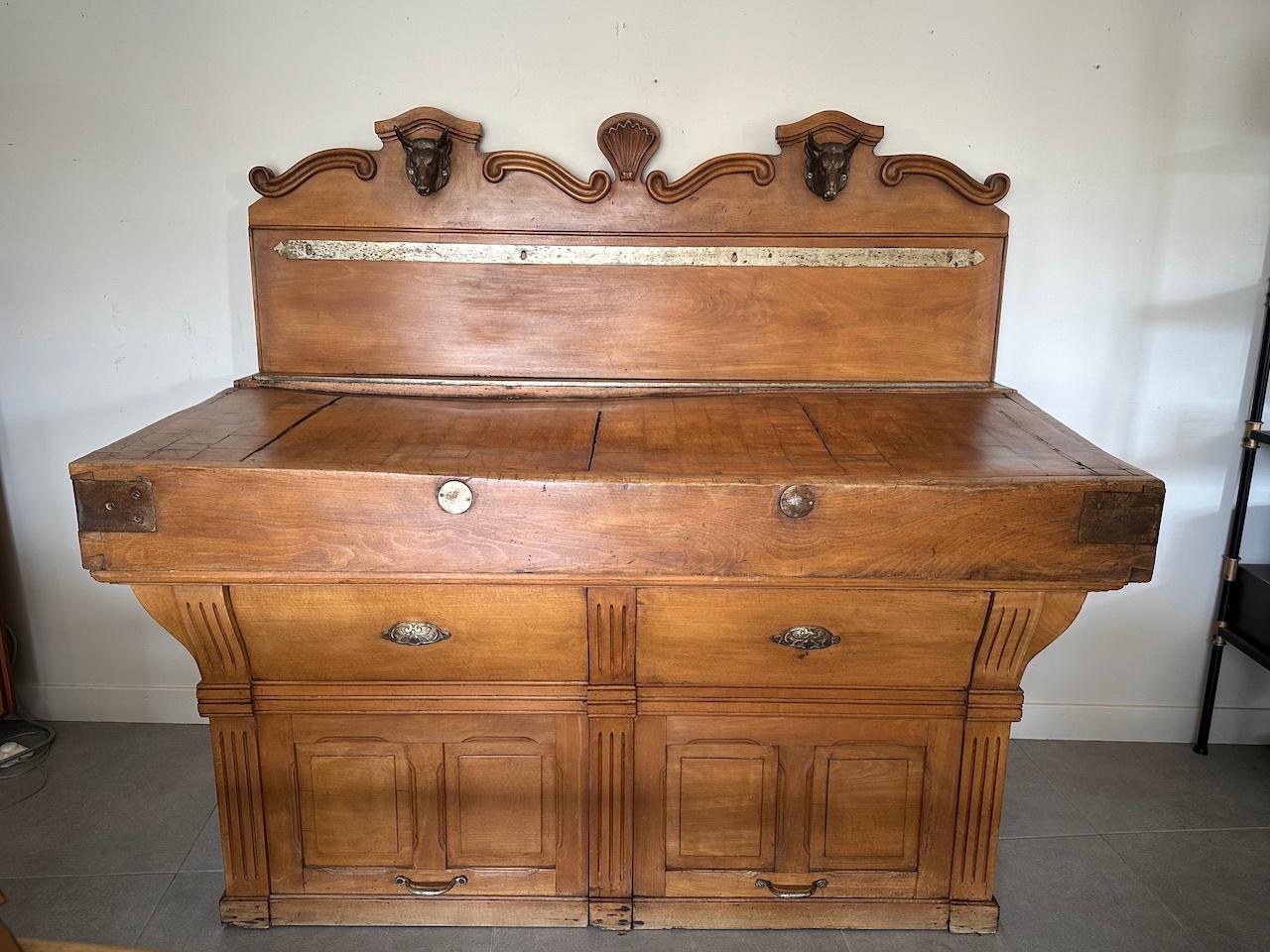 Rare piece! Magnificent butcher block dating from the beginning of the 20th century in beech and standing wooden top allowing it to be scraped both vertically and horizontally (to remove fat).
Two cast iron ox heads adorn the upper part. A metal