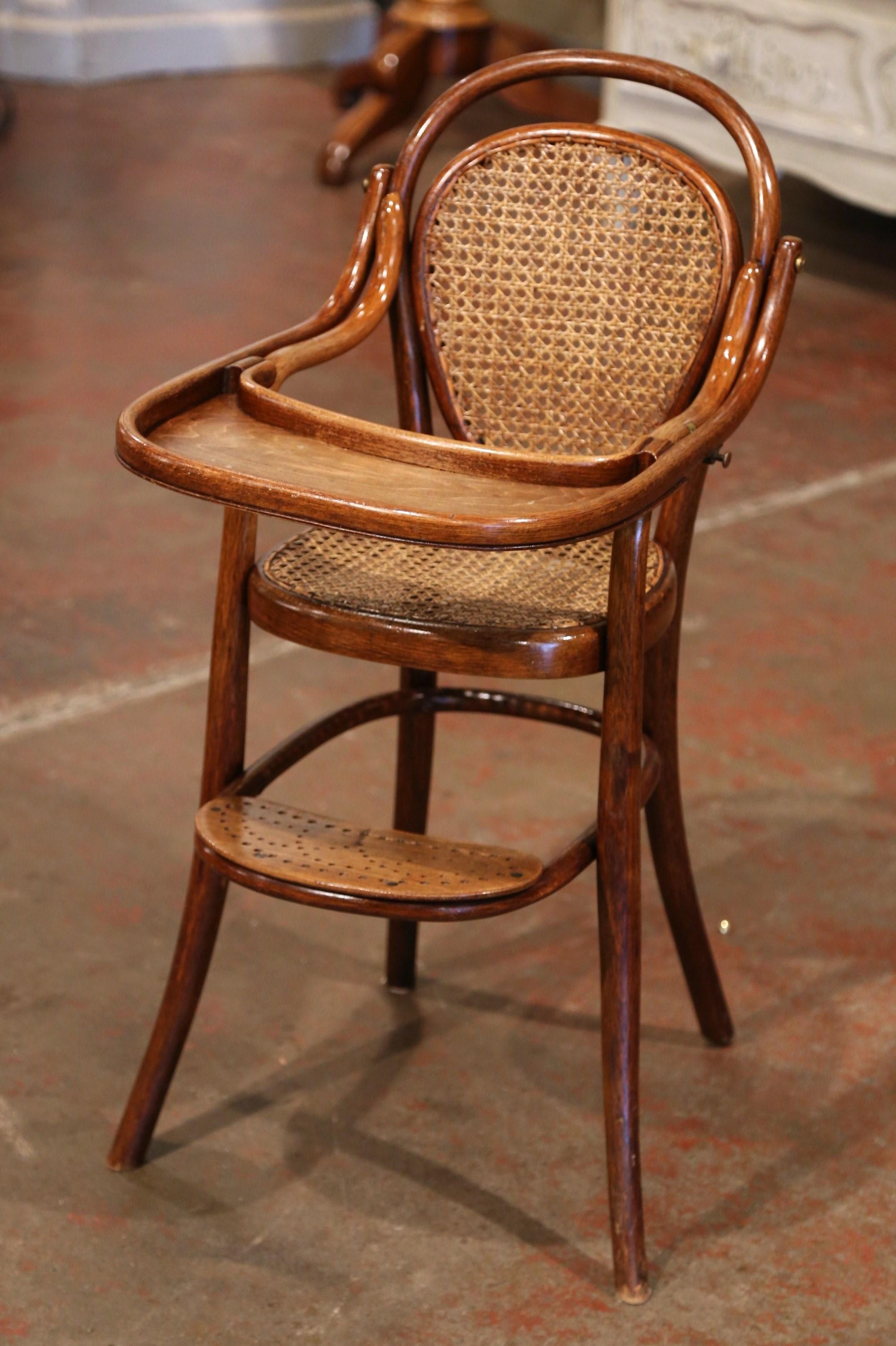 Feed your child in style in the antique and sturdy Art Deco high chair; crafted in France of bentwood circa 1920 attributed to Michael Thonet (1796-1871), the child chair stands on four curved legs embellished with a pierced footrest on the front;