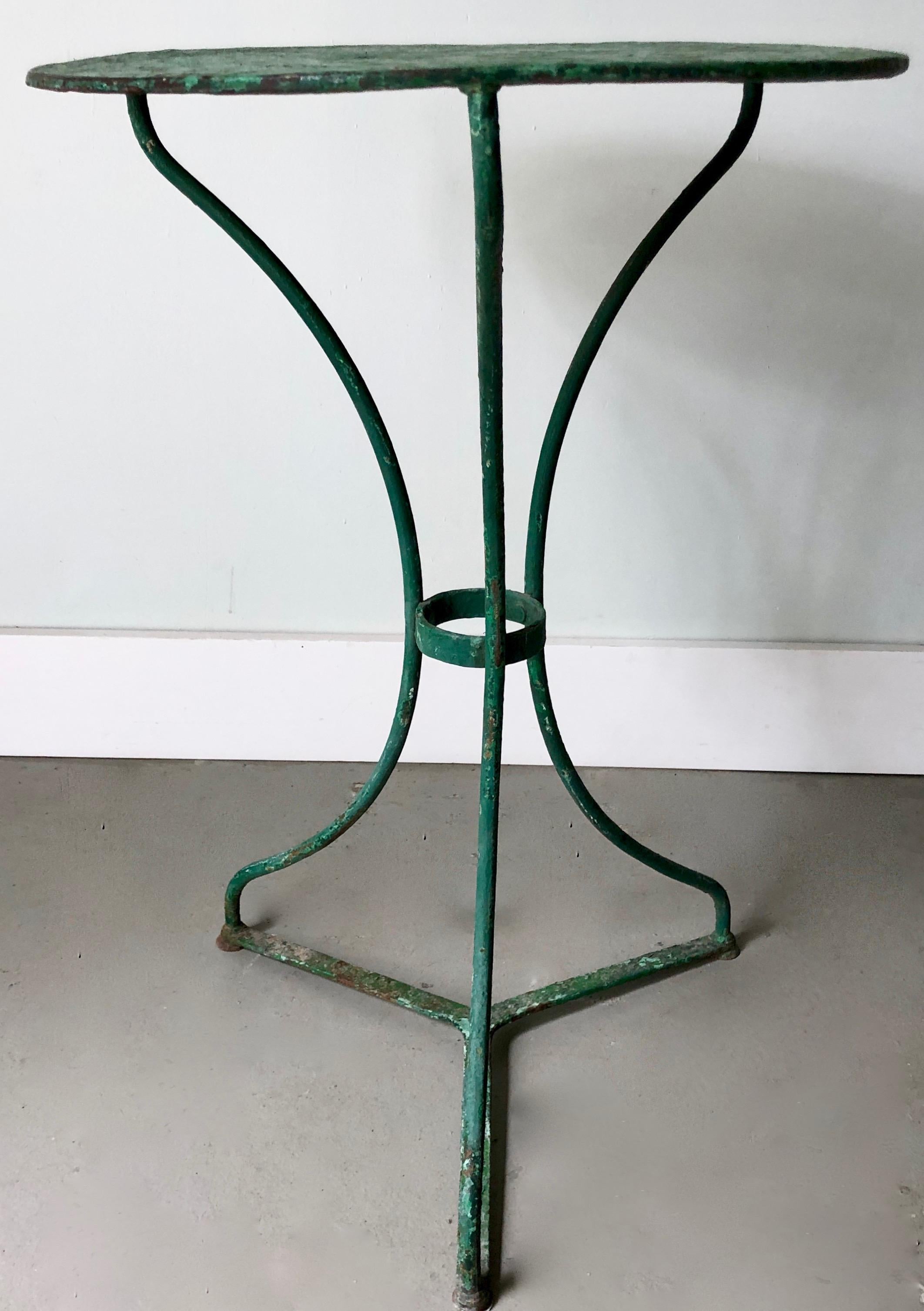Early 20th century French bistro table with old worn layers of green/turquase tones. Riveted, with shapely wrought iron legs and sheet metal top.