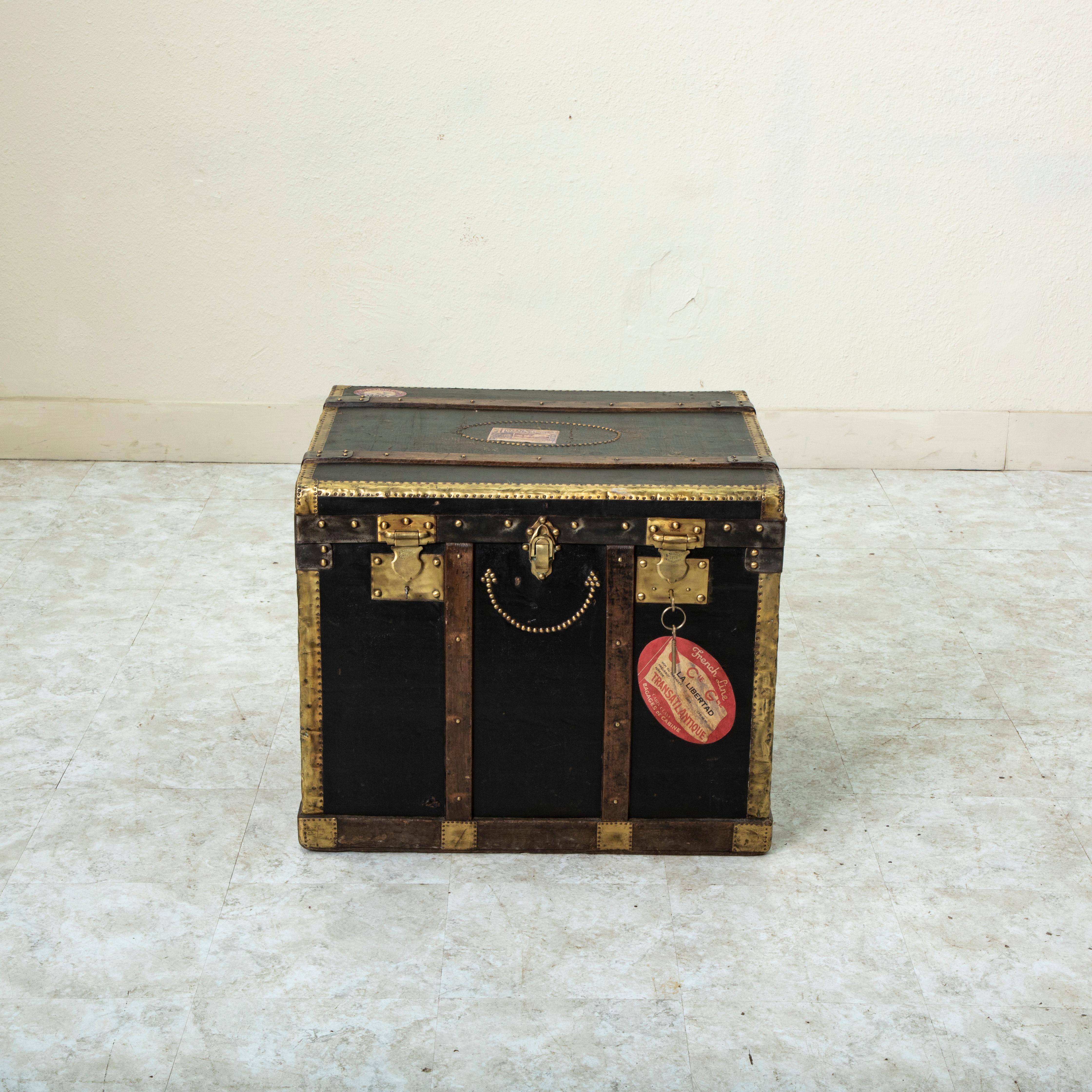 This French wooden steam trunk from the early twentieth century is covered in black leather and features wooden runners and brass corners that offered protection from damage when traveling. Its original leather handles are still intact. The locks