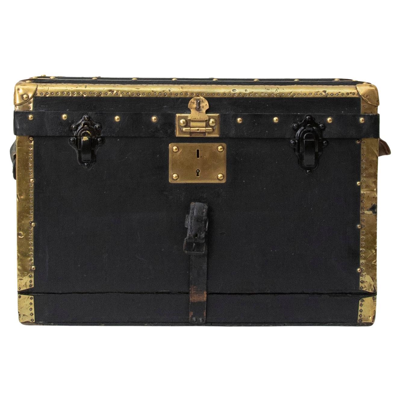 Originally used in the 1920's to carry goods for a traveling salesman, this small scale French wooden traveling trunk is covered in black leather and features wooden runners and brass corners that offered protection from damage when traveling. Its