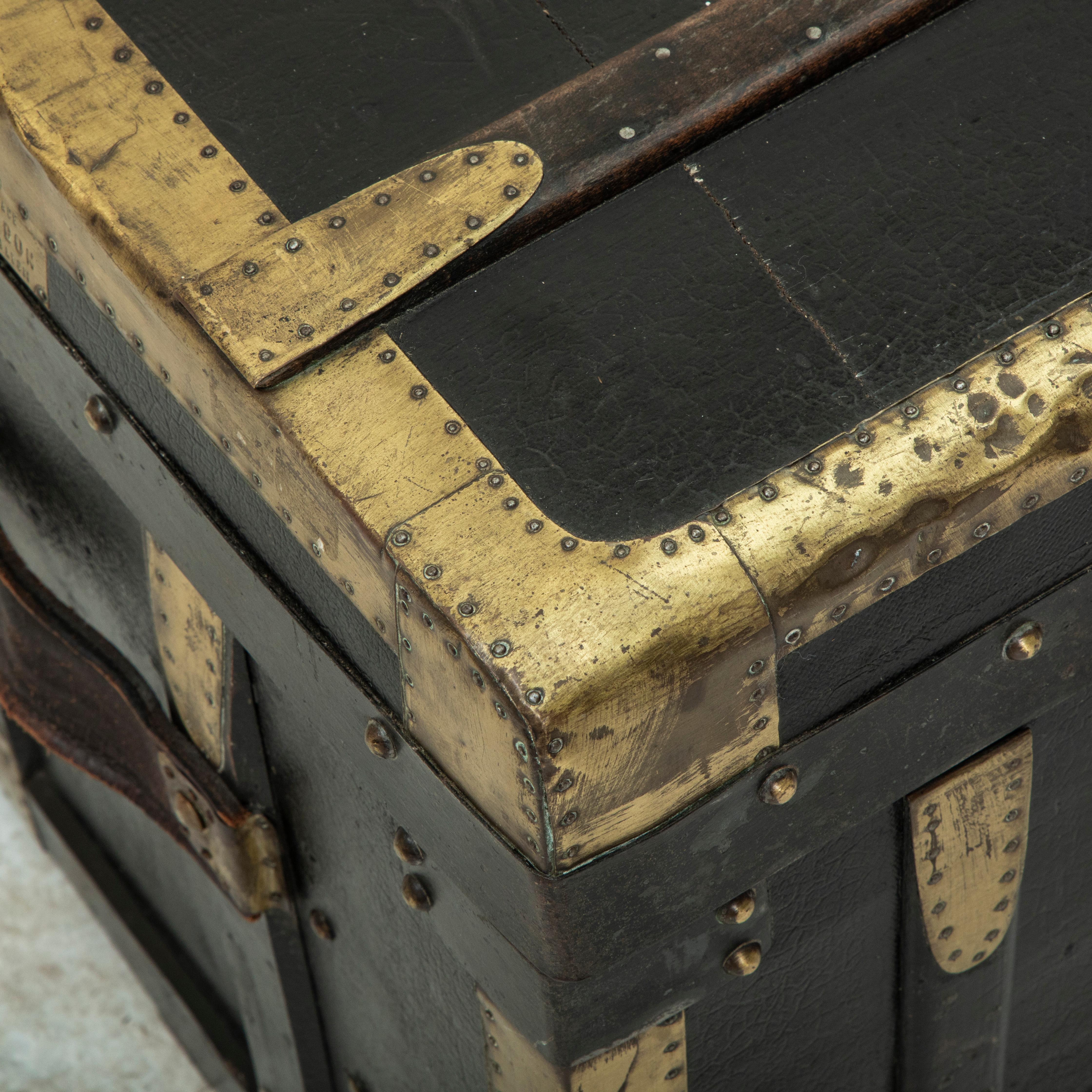This French wooden steam trunk from the early twentieth century is covered in black leather and features wooden runners and brass corners that offered protection from damage when traveling. Its original leather handles are still intact. A leather
