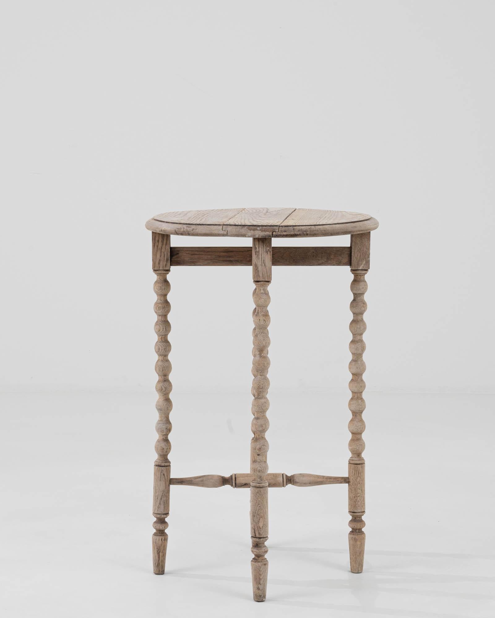 This early 20th-century French drop leaf table is a remarkable piece of history, showcasing the natural beauty and durability of bleached oak. Its soft, weathered hue brings a sense of light and rustic elegance to any space. Crafted with a keen eye