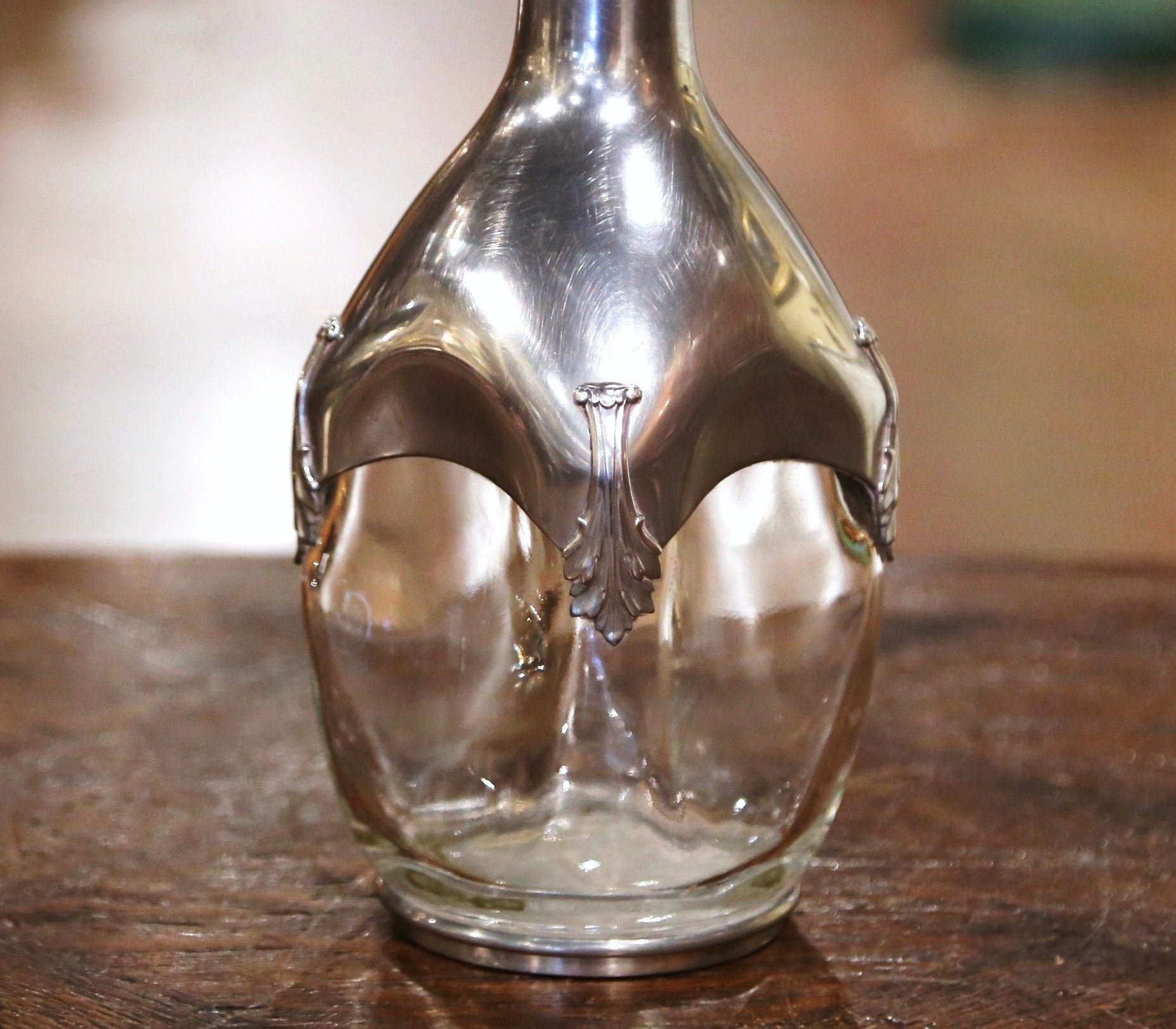 Serve your favorite Bordeaux with style in this elegant antique decanter. Crafted in France circa 1920, the carafe stands on a round silver base over the blown glass, and dressed with a silvered pewter coat decorated with repousse acanthus leaf