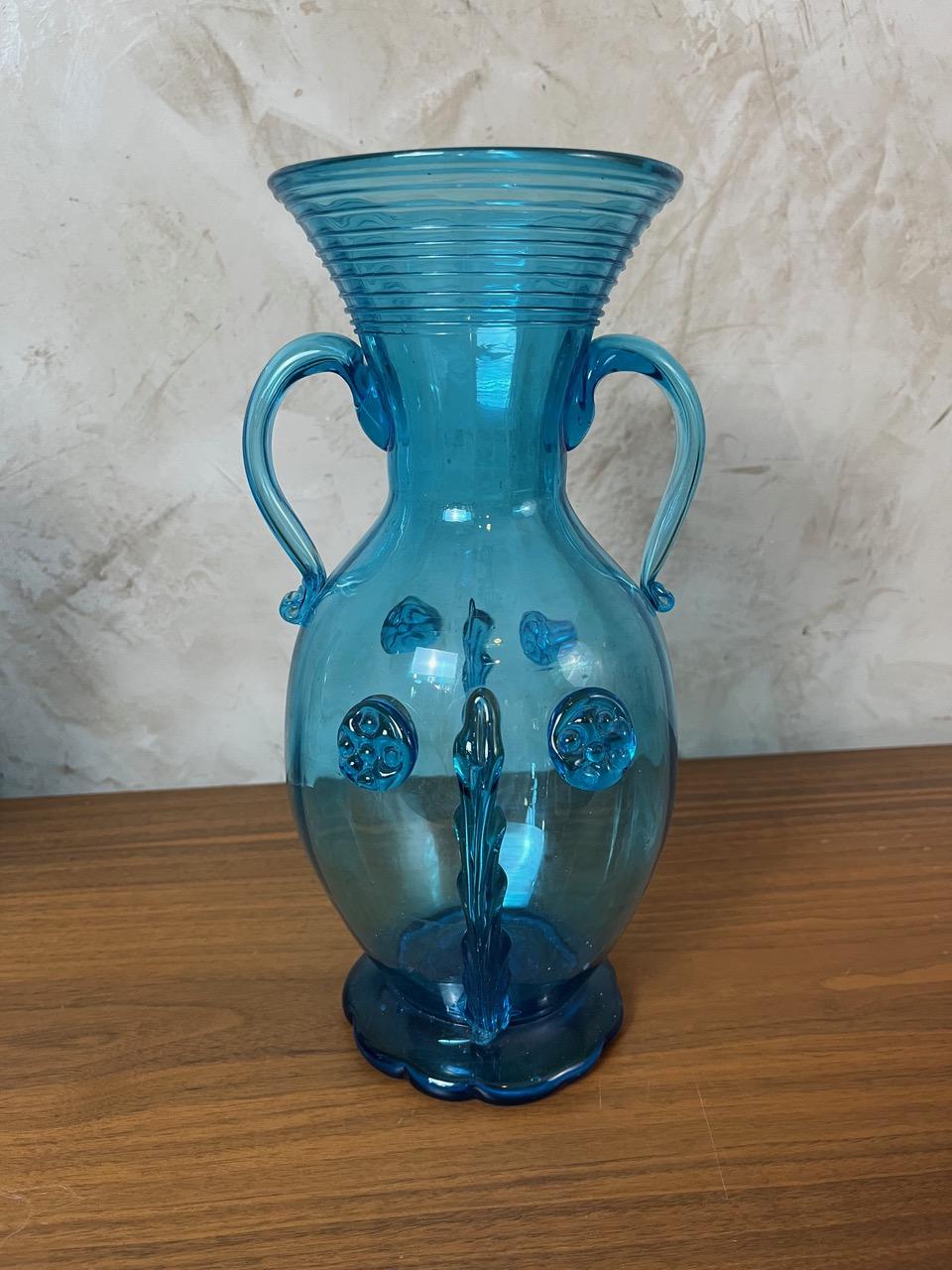 Egalisez votre intérieur avec ce vase en verre soufflé très élégant. Sa couleur bleu translucide et son design inspiré des amphores antiques, accentué par des détails uniques, en font une pièce décorative incontournable.