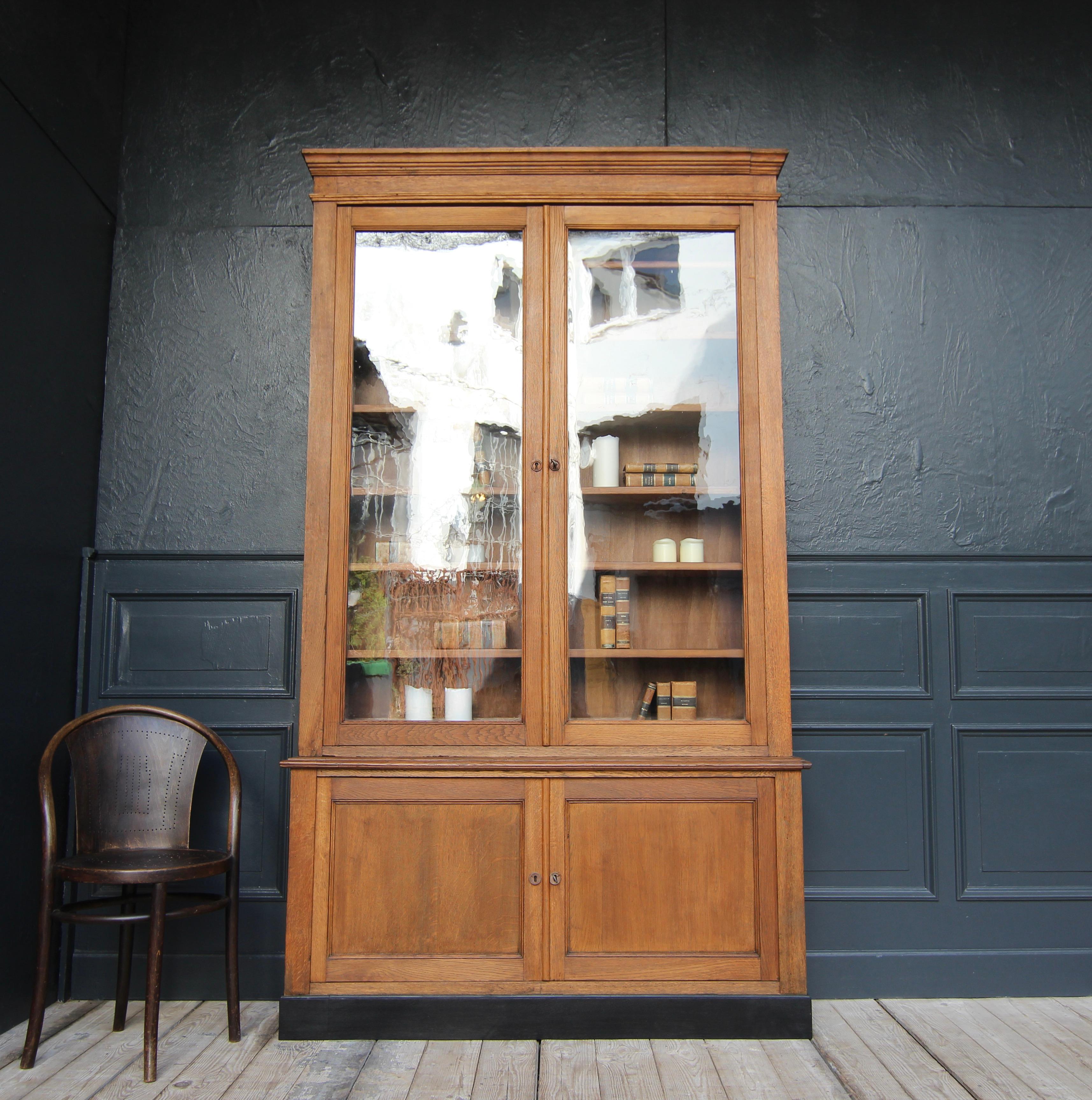 French bookcase or display cabinet from the shop fittings of a pharmacy. Around 1910.

A rare original in a classic timeless design with great proportions.

Straight-lined four-door body in oak and poplar wood, consisting of a base cabinet standing