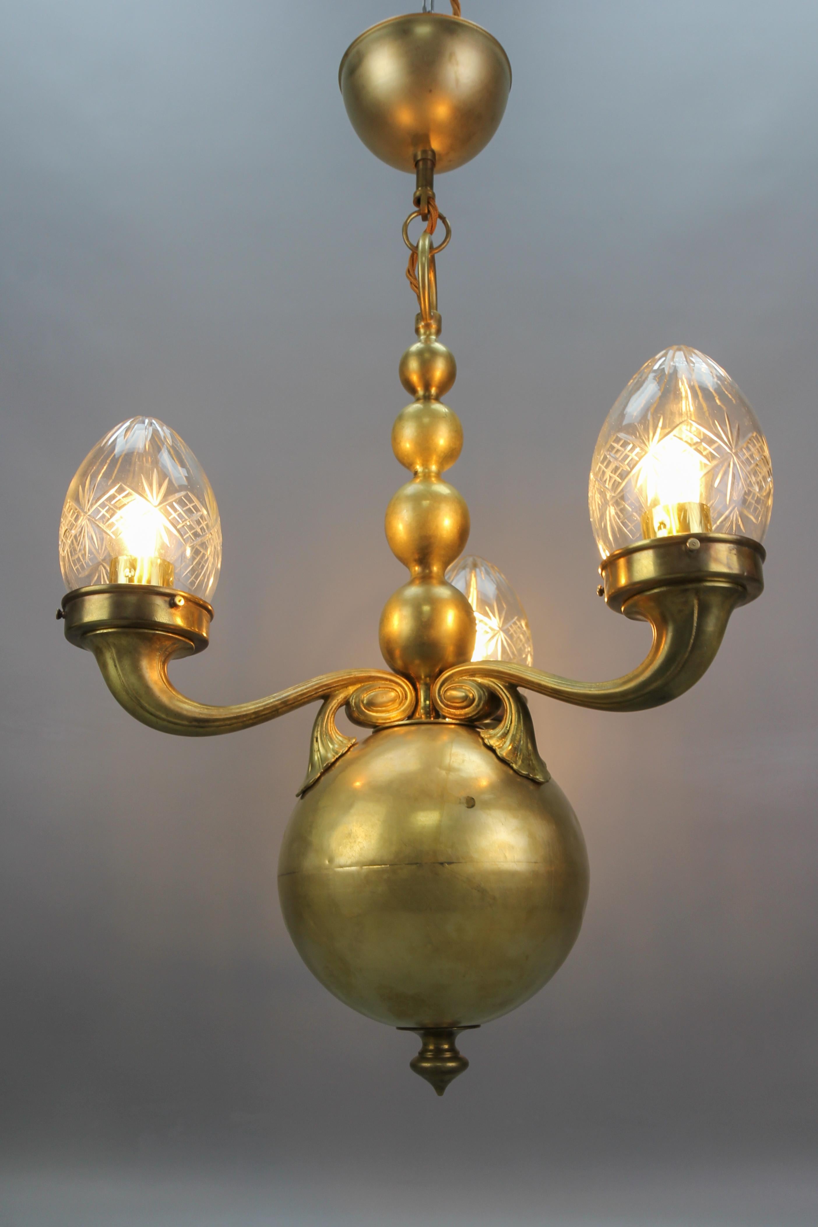 French brass and clear, cut glass three-light chandelier from the early 20th century.
An impressive and elegant three-arm chandelier made of brass. Each arm with an oviform clear, cut glass lampshade and a socket for an E27 (E26) size light