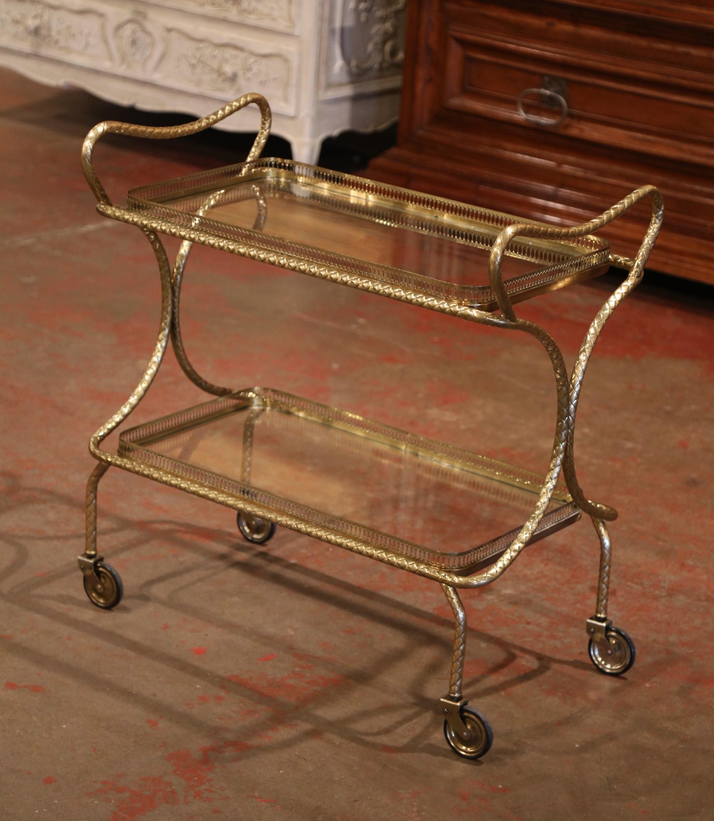 This elegant, vintage rolling bar cart was created in France, circa 193. Attributed to Maison Jansen, the rectangular desert table has a brass frame, small wheels with rubber tires over curved legs, and two rectangular plateaus topped with glass