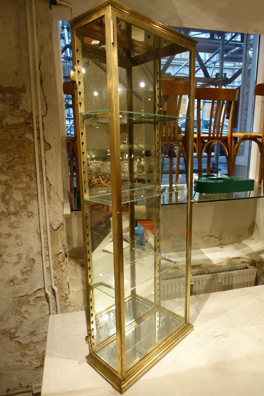 Elegant, tall and slim French brass bistro vitrine unit, from Avignon in the early 1900s. Originally, it would have been hung on a wall and used as an AVEC cabinet in a bistro, to store and display cognacs and liquors etc.

Three glass shelves sit