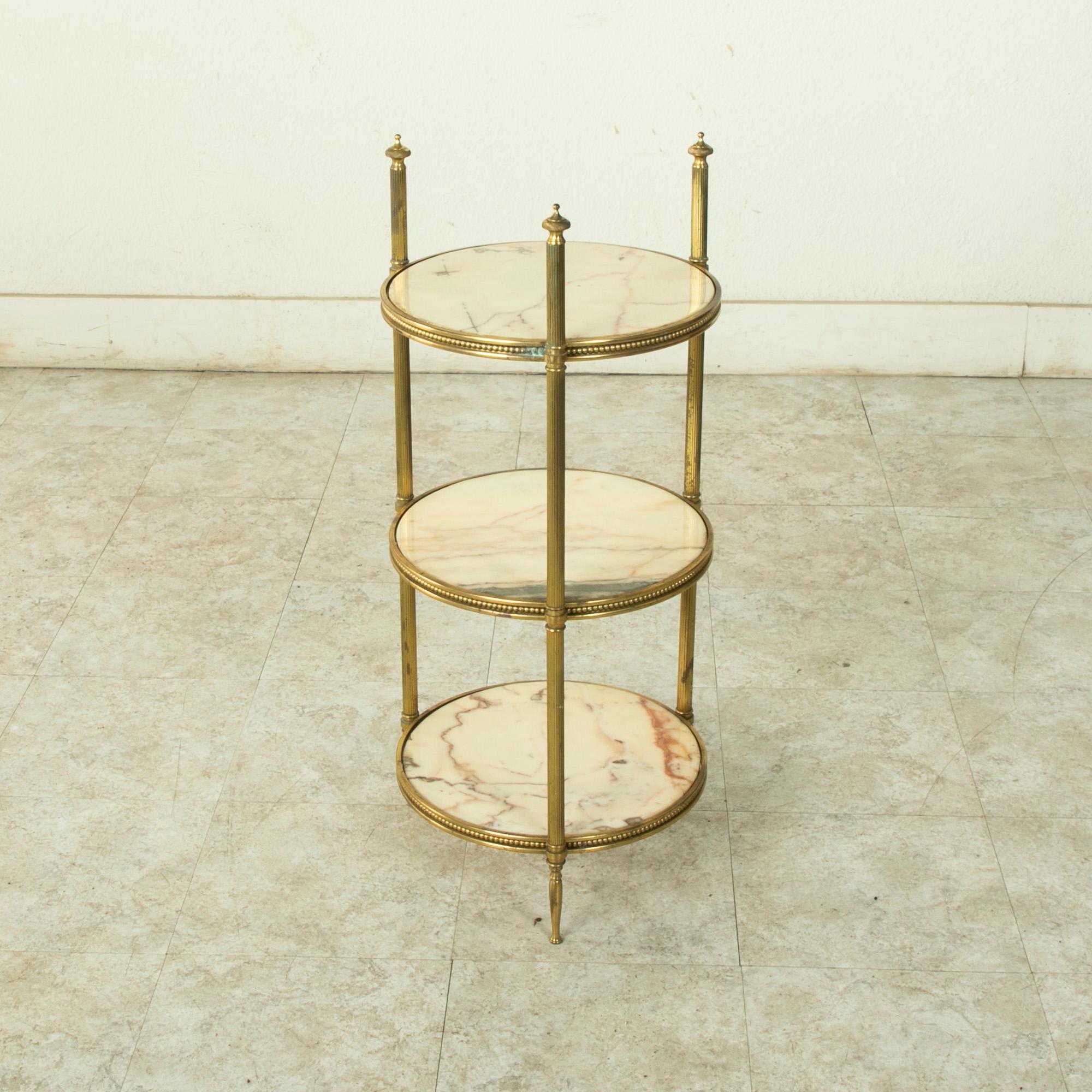 Originally used in a French pastry shop for display on top of the counter, this early twentieth century brass presentation server features three marble shelves. The shelves rest on brass circular supports detailed with beading. The three fluted