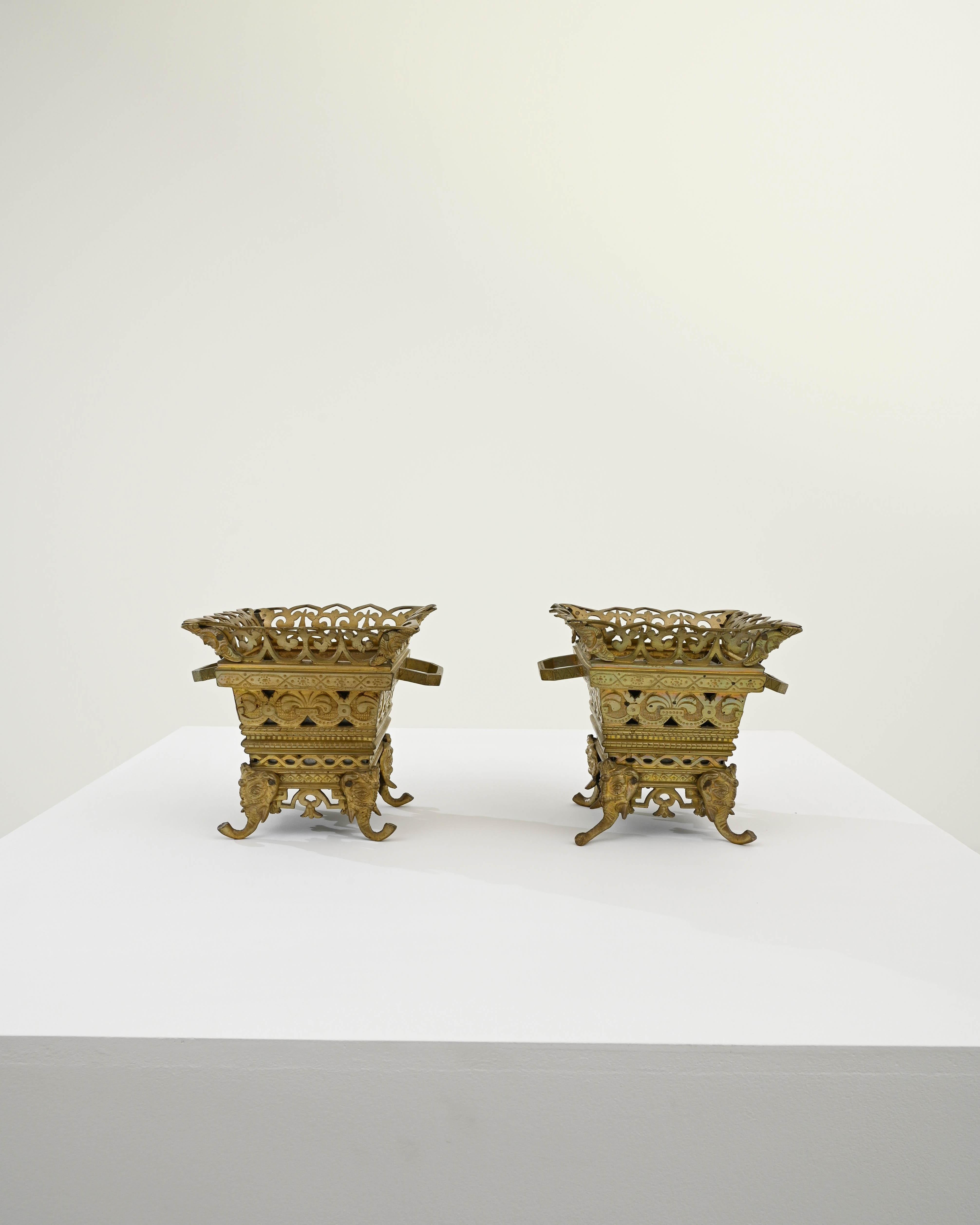 A pair of early 20th century French metal planters. Created in an illustrious Belle Époque sensibility, these identical brass planters dazzle the eye with a barrage of painstakingly shaped details. Geometric patterns, scroll motifs, and lovely