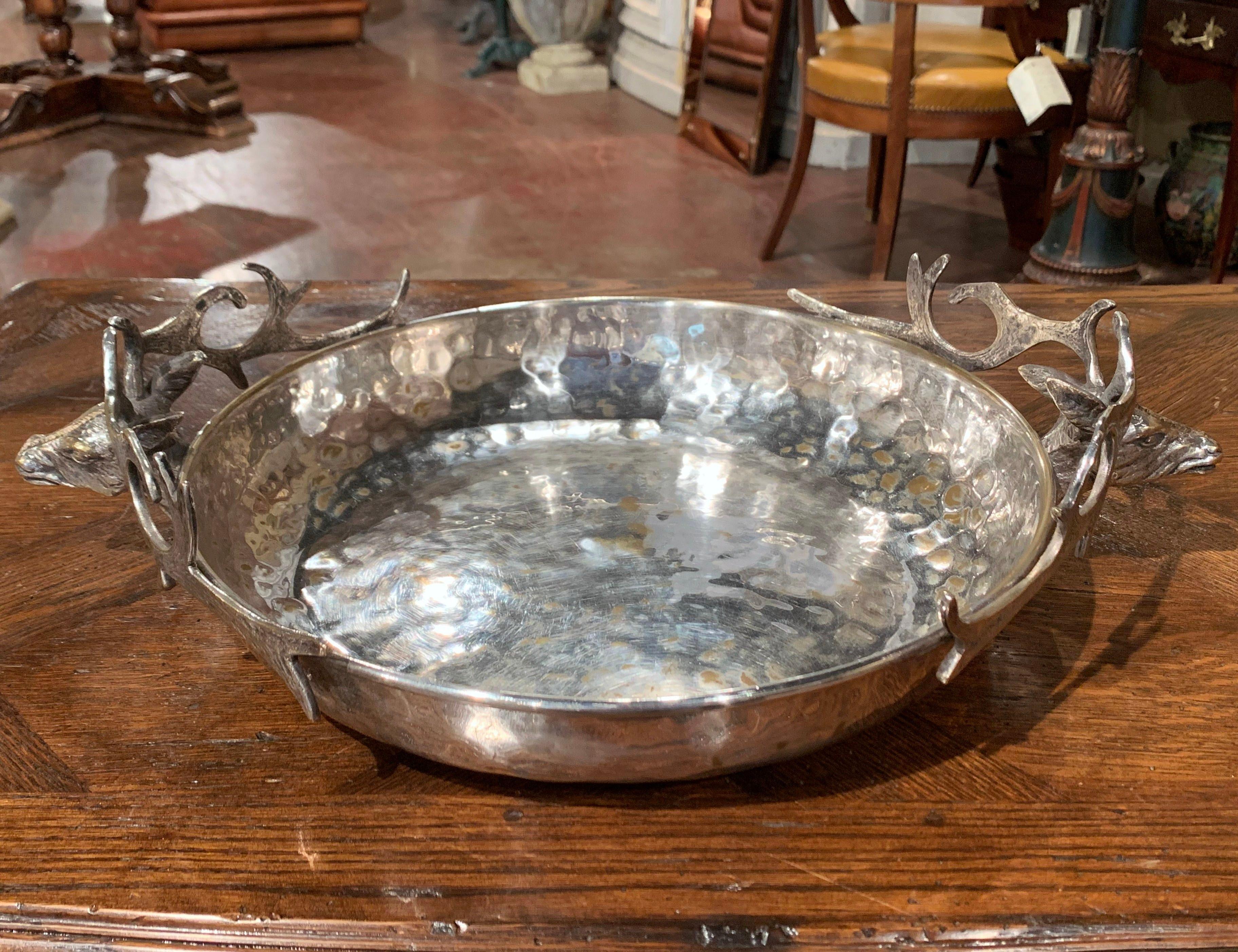 This decorative bowl was created in France, circa 1920. Round in shape and made of brass and sliver plated, the traditional centrepiece features a pair of deer with antlers handles on either side for countryside flair. This unique, rustic dish is in
