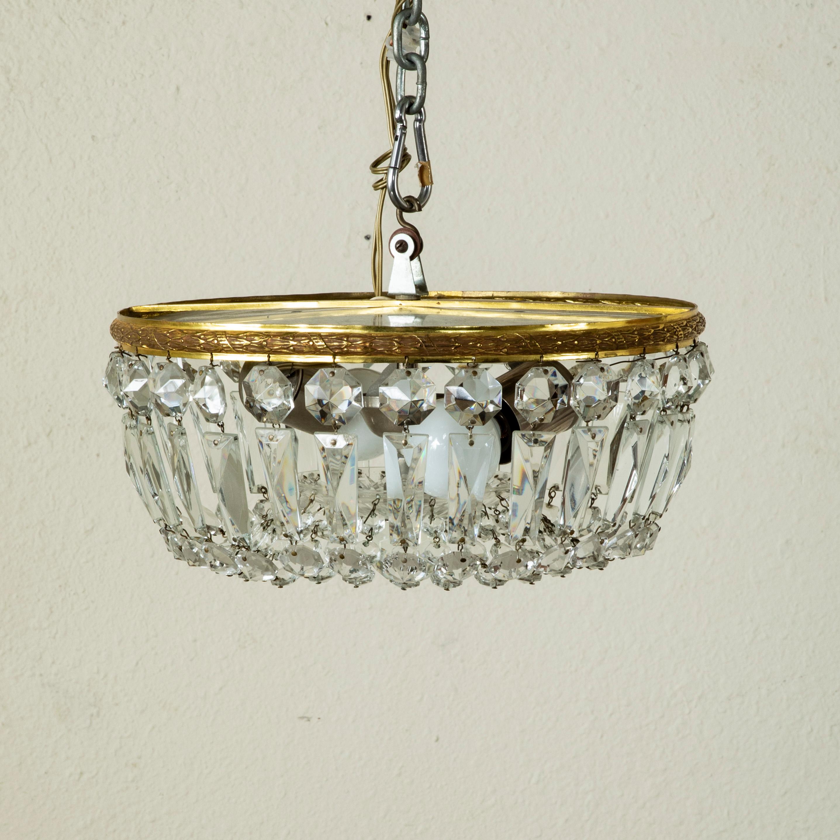 This small scale early twentieth century French flush mount chandelier features an upper bronze ring with a laurel and twisted ribbon motif. Multi-faceted strings of crystal beading drape to meet a central crystal ball. An ideal chandelier for a