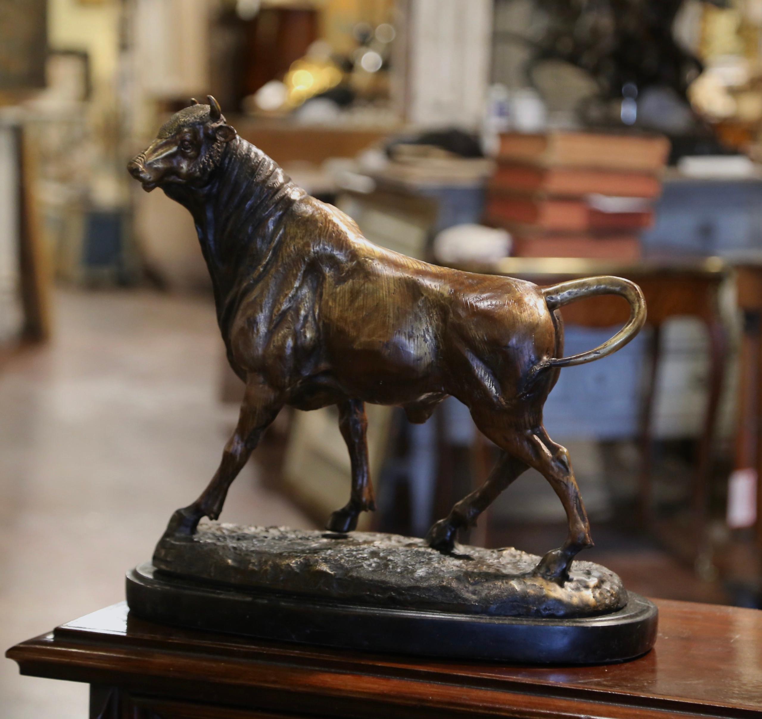 Dekorieren Sie das Büro oder Arbeitszimmer eines Mannes mit dieser antiken Stierskulptur. Die um 1920 in Frankreich geschaffene Bronzeskulptur steht auf einem ovalen Sockel aus schwarzem Marmor und zeigt ein trotziges Rind, das auf felsigem Grund