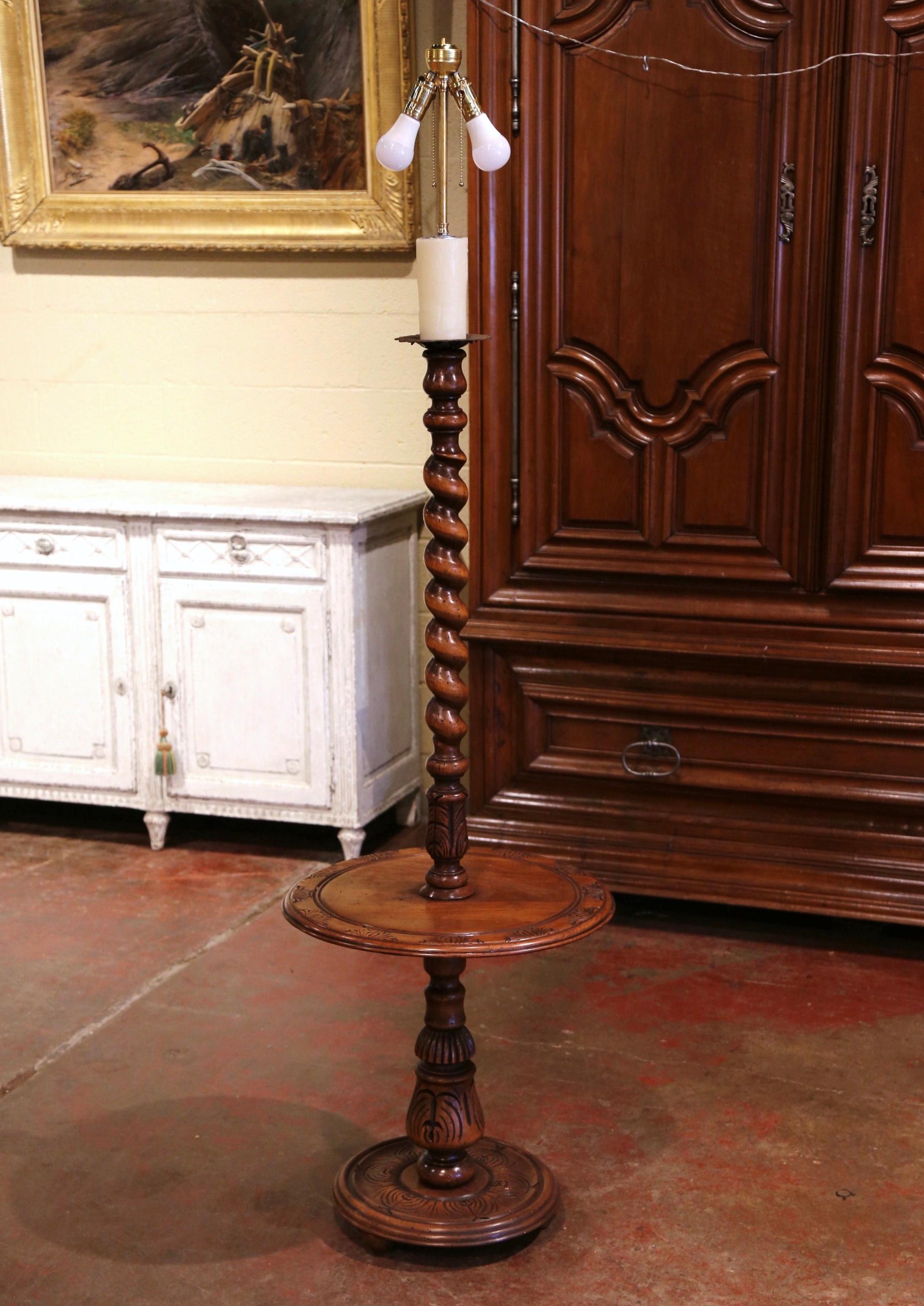 This unique, antique floor lamp was crafted in Northern France, circa 1920. Seated on three small feet over a circular base decorated with floral and leaf motifs, the lamp features a carved barley twist stem with a round ledge table in the center
