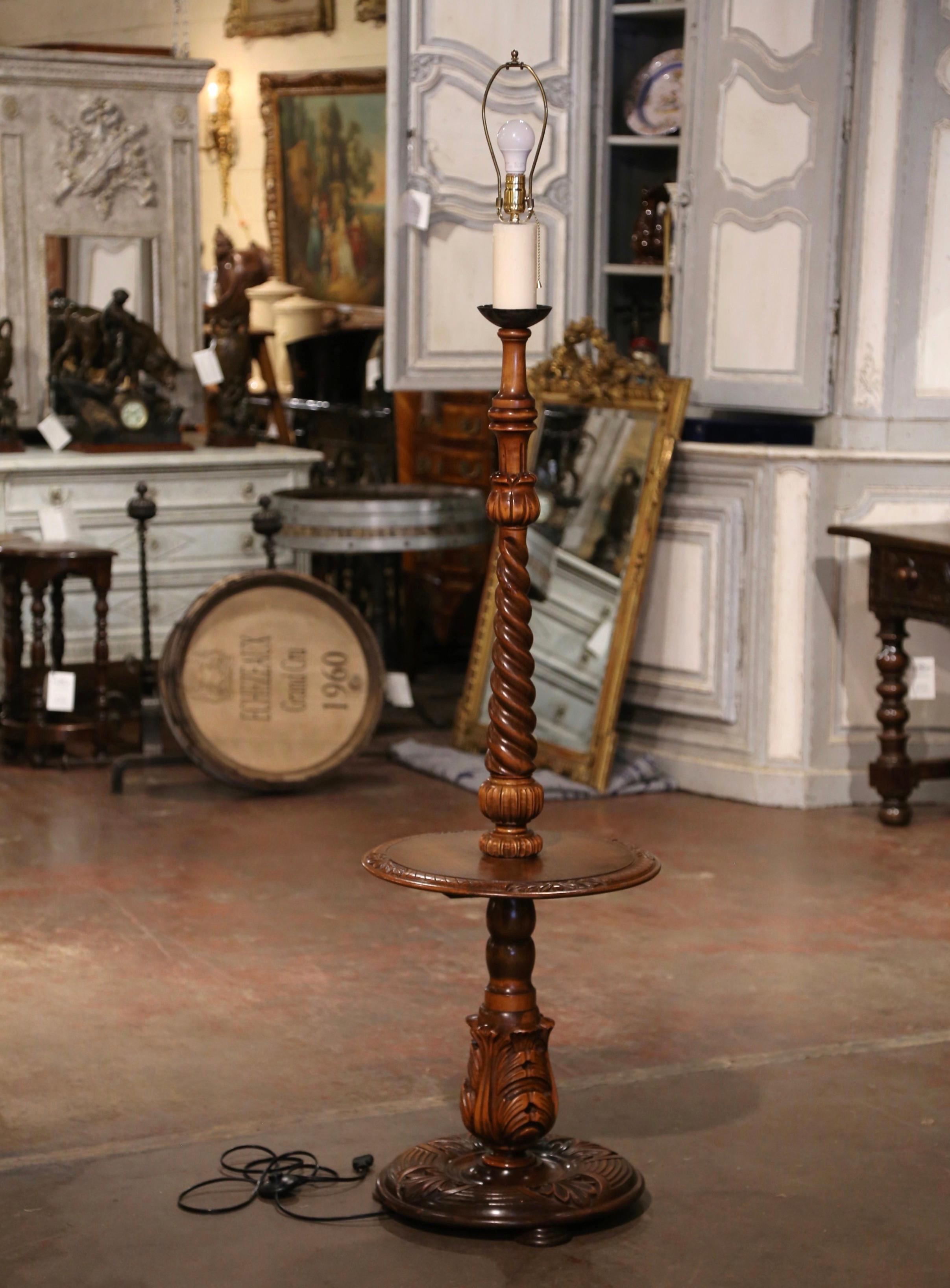 This unique, antique floor lamp was crafted in Northern France, circa 1920. Standing on three bun feet over a circular base embellished with hand carved foliage decor and acanthus leaves, the lamp boasts a barley twist stem, with a central round