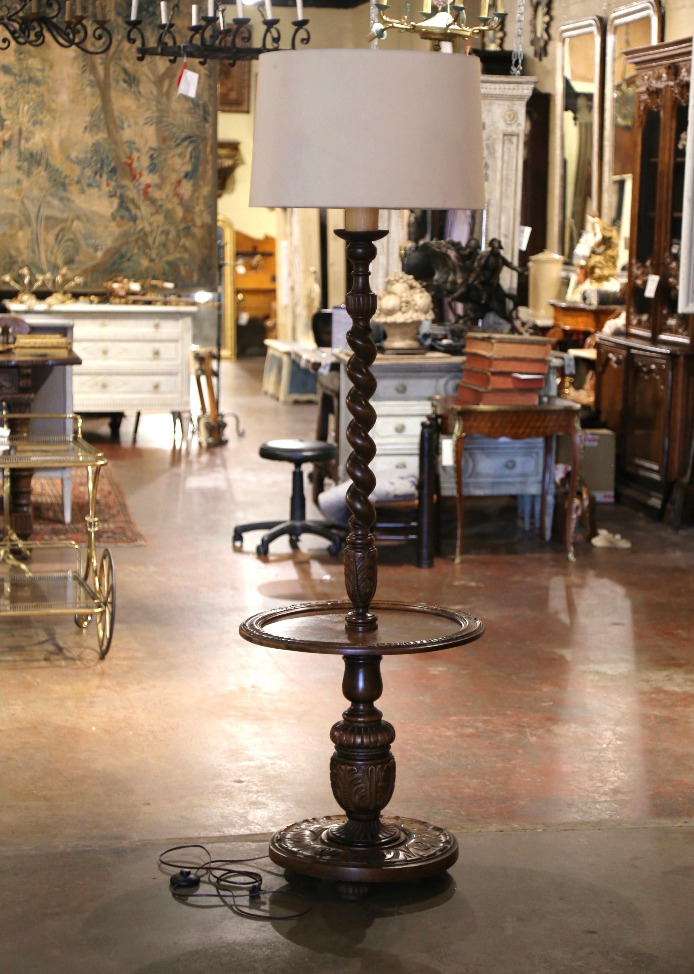 This unique, antique floor lamp was crafted in Northern France, circa 1920. Standing on three bun feet over a circular base embellished with hand carved foliage decor and acanthus leaves, the lamp boasts a barley twist stem, with a central round