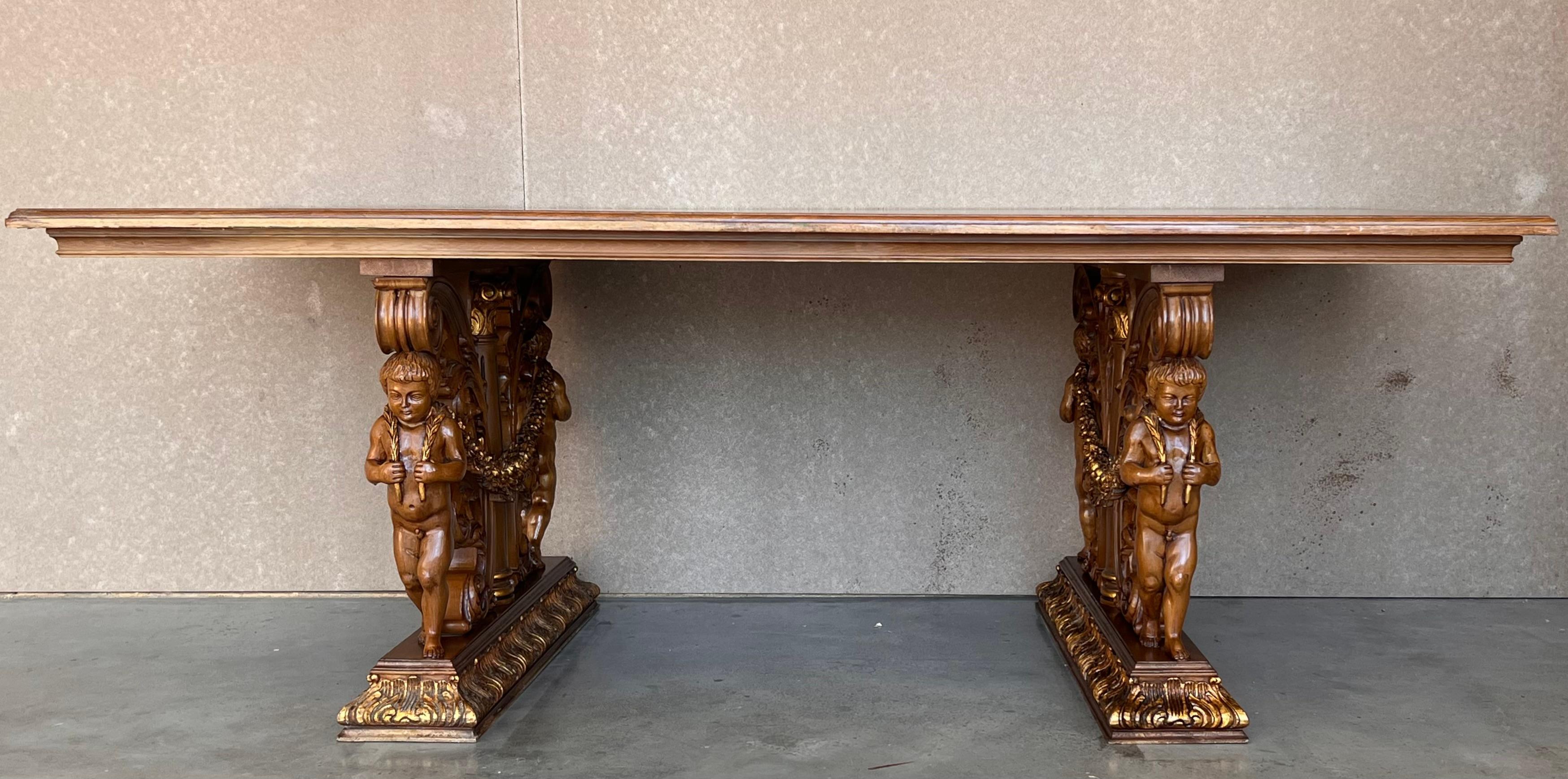 Esta elegante y gran mesa de comedor antigua se fabricó en Francia, hacia 1900. Apoyada sobre dos patas de pedestal talladas y decoradas con motivos de follaje y dos querubines en cada pedestal , la mesa de estilo Luis XIII está vestida con un