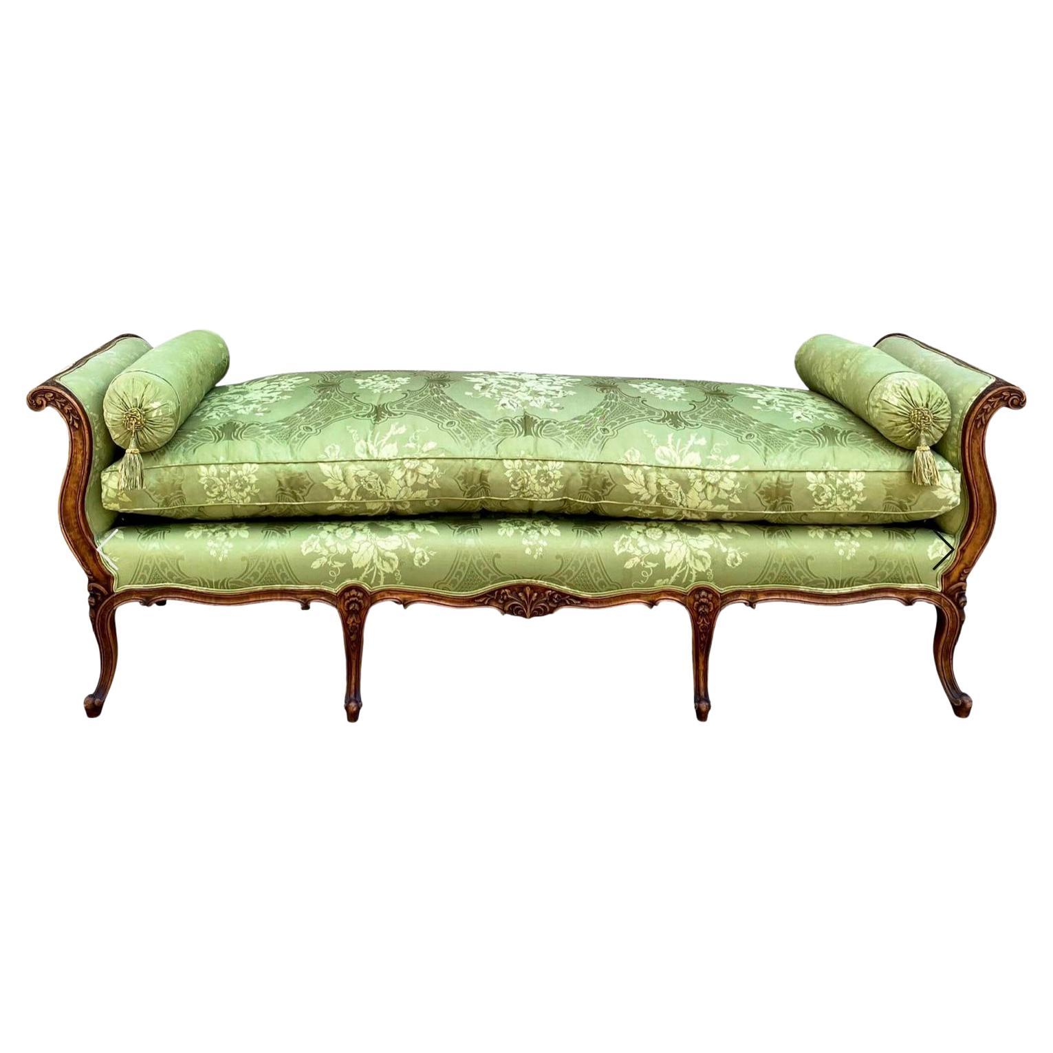 This is a lovely early 20th century French carved daybed in vintage embroidered green silk. The frame is in very good condition. It has a nice, thick down cushion. The upholstery on one side is faded, but the other has no issues.