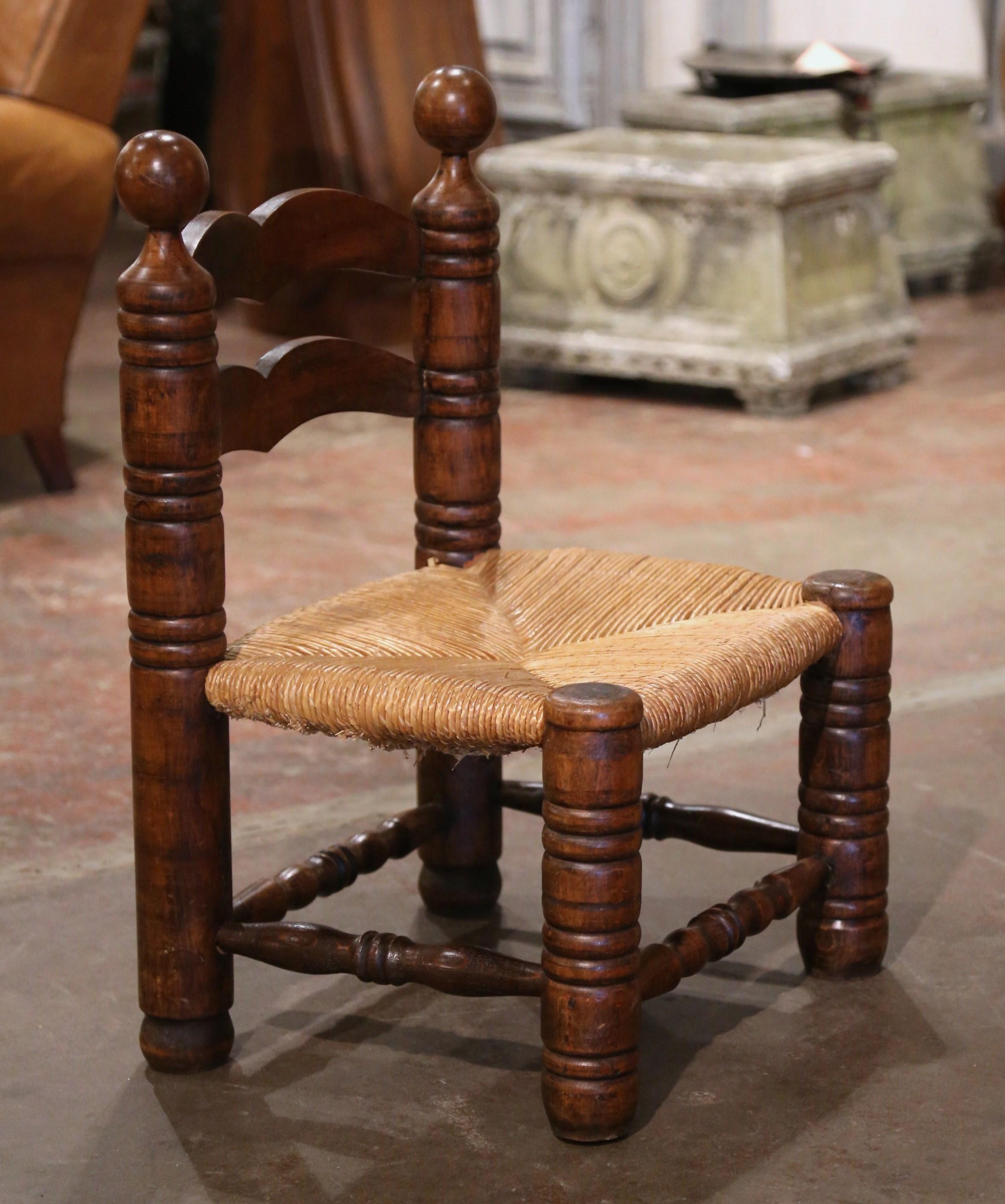 This very comfortable antique ladder back chair was crafted in Normandy, France circa 1940. Built in oak and beech wood and done in the style of Charles Dudouyt, the armchair sits on round turned legs and features two ladders in the back embellished